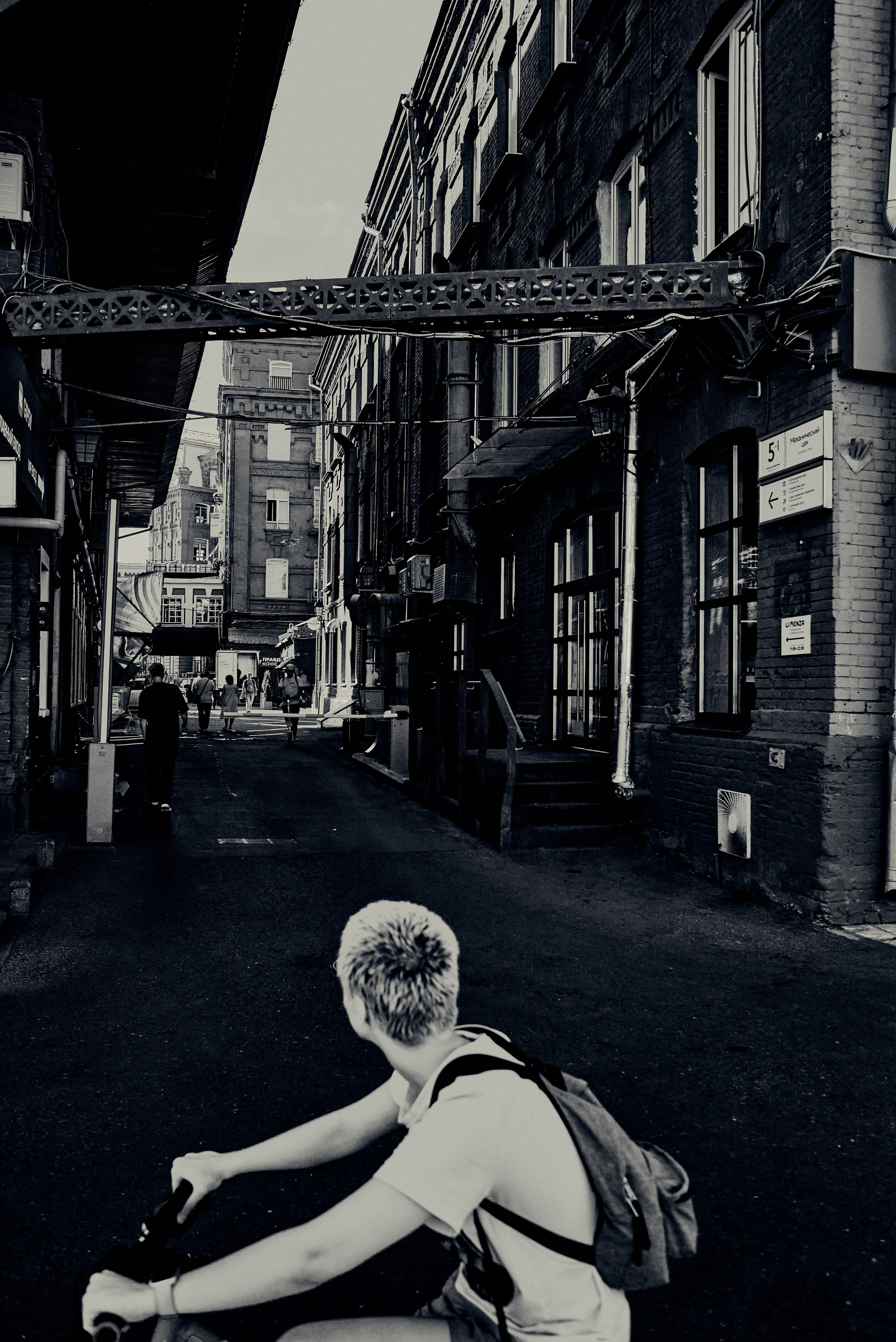 Велосипедист смотрит в  подворотню. Стрит фотография. Город Москва 2024 год. Фотограф Александр Гладкий