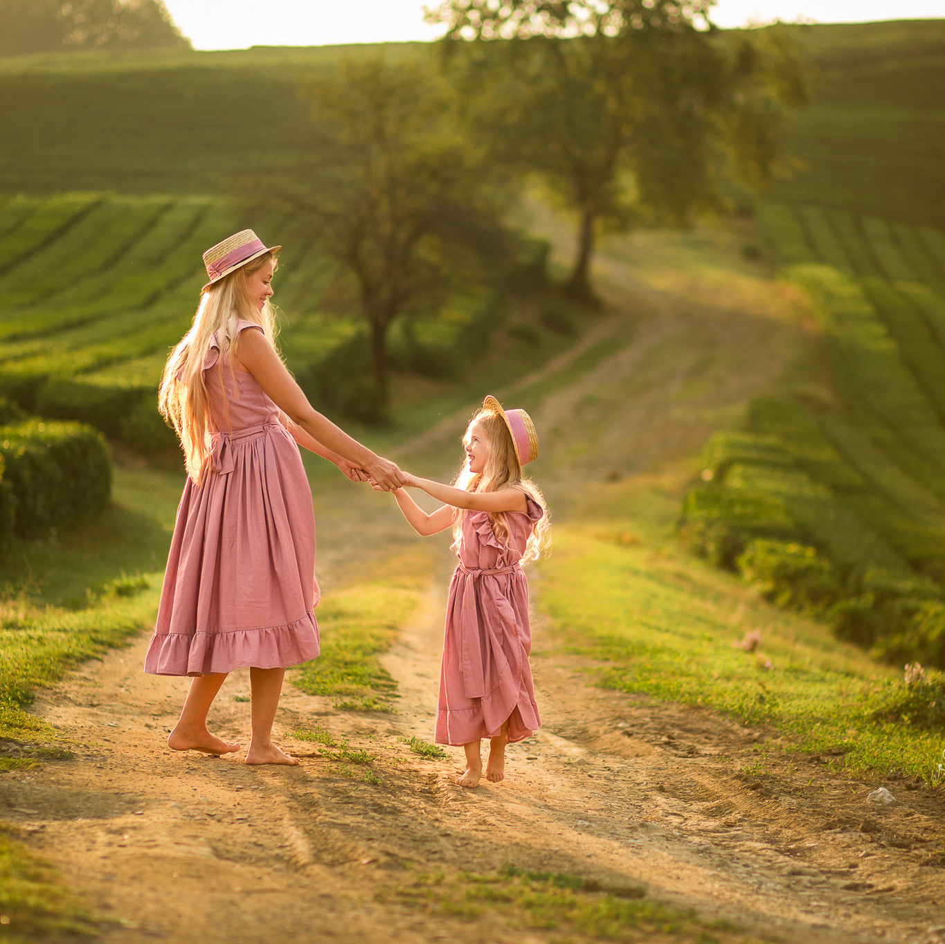 Мама с дочкой в одинаковых платьях гуляют на чайной плантации на восходе солнца