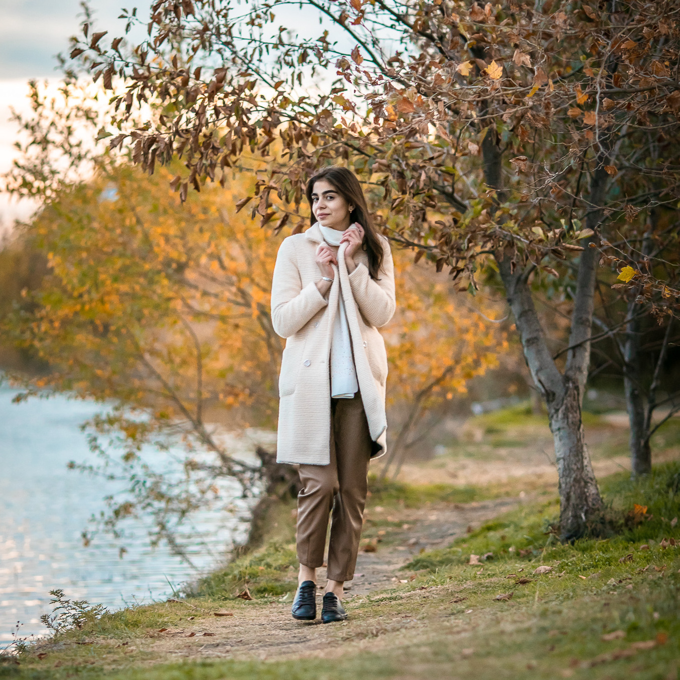 Красивая девушка гуляет у реки на фоне осеннего леса 