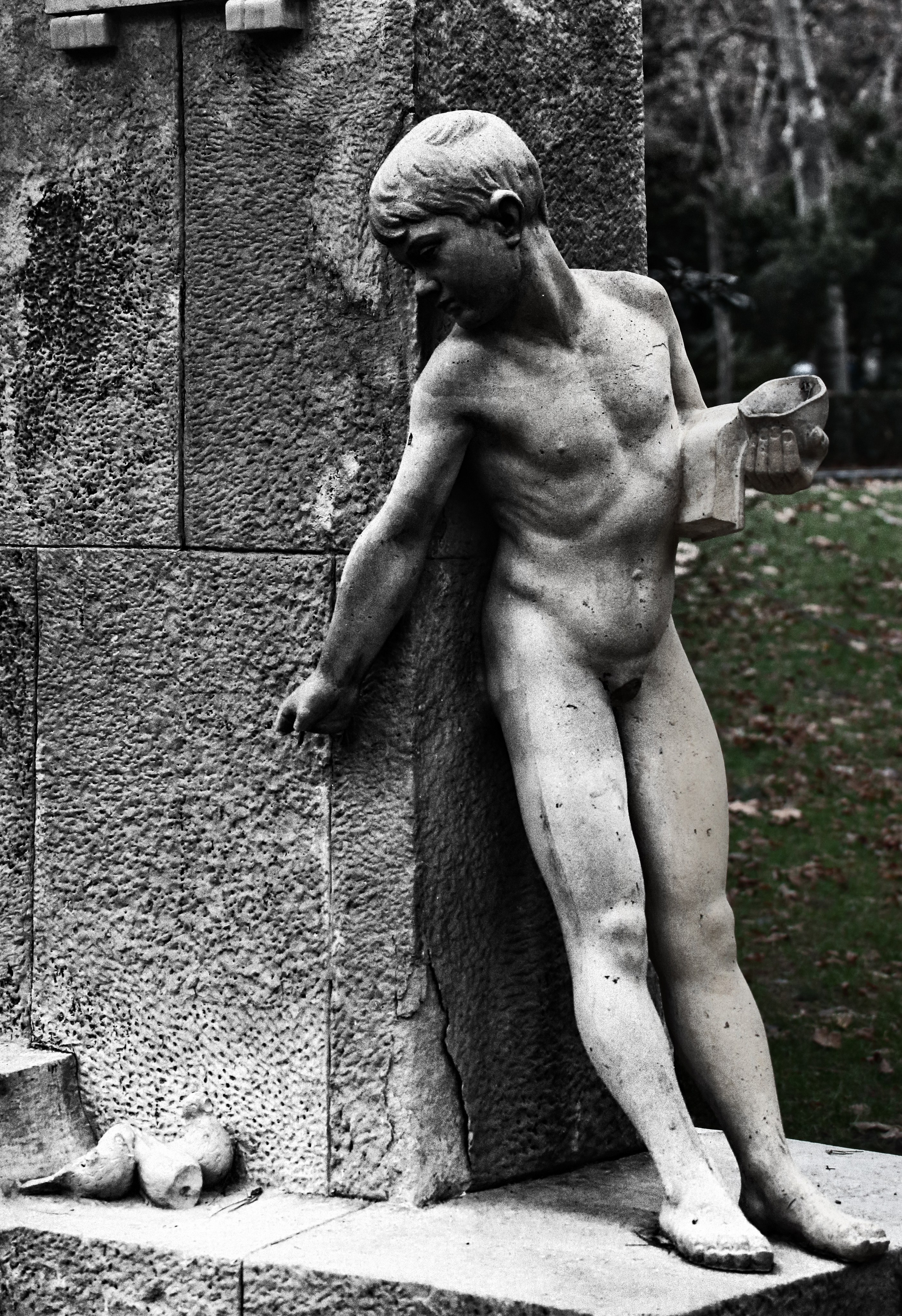 Классическая скульптура обнаженного юноши прислонившегося к стене, черно-белое фото античной статуи, кладбищенское искусство