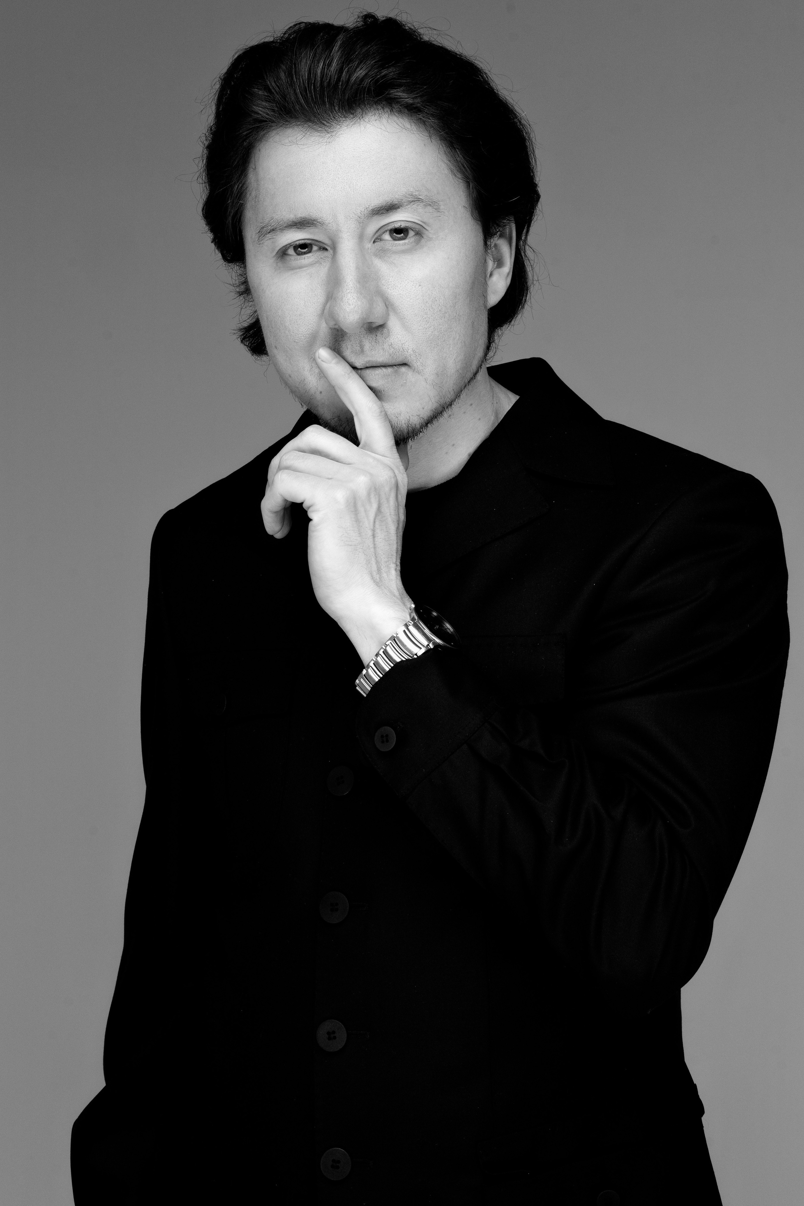 Руки художницы держат кисти и перо. Крупный план, бежевый плащ на фоне.