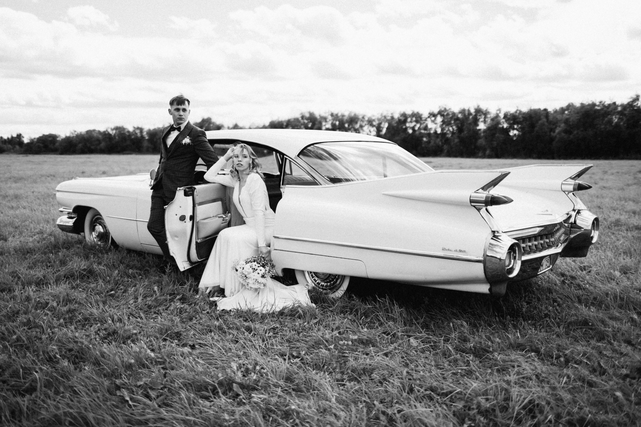 Свадебная фотосессия в Архангельске: романтические моменты, стильной пары в поле на фоне винтажного автомобиля Cadillac 1959 