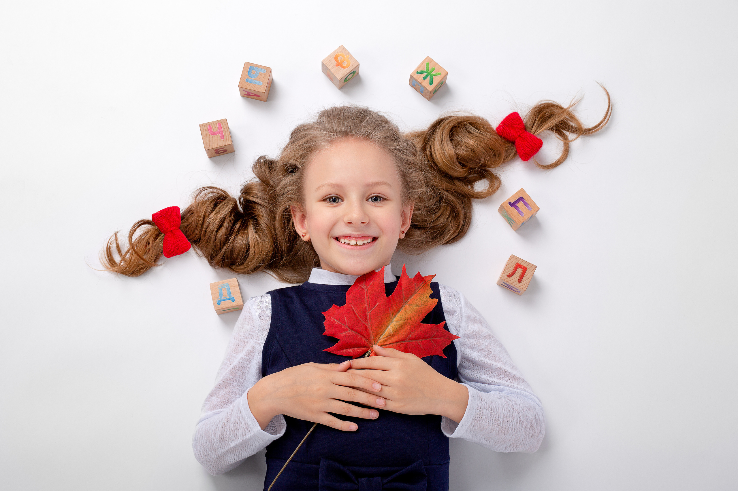 Кленовый лист в руках первоклашки, банты и кубики.