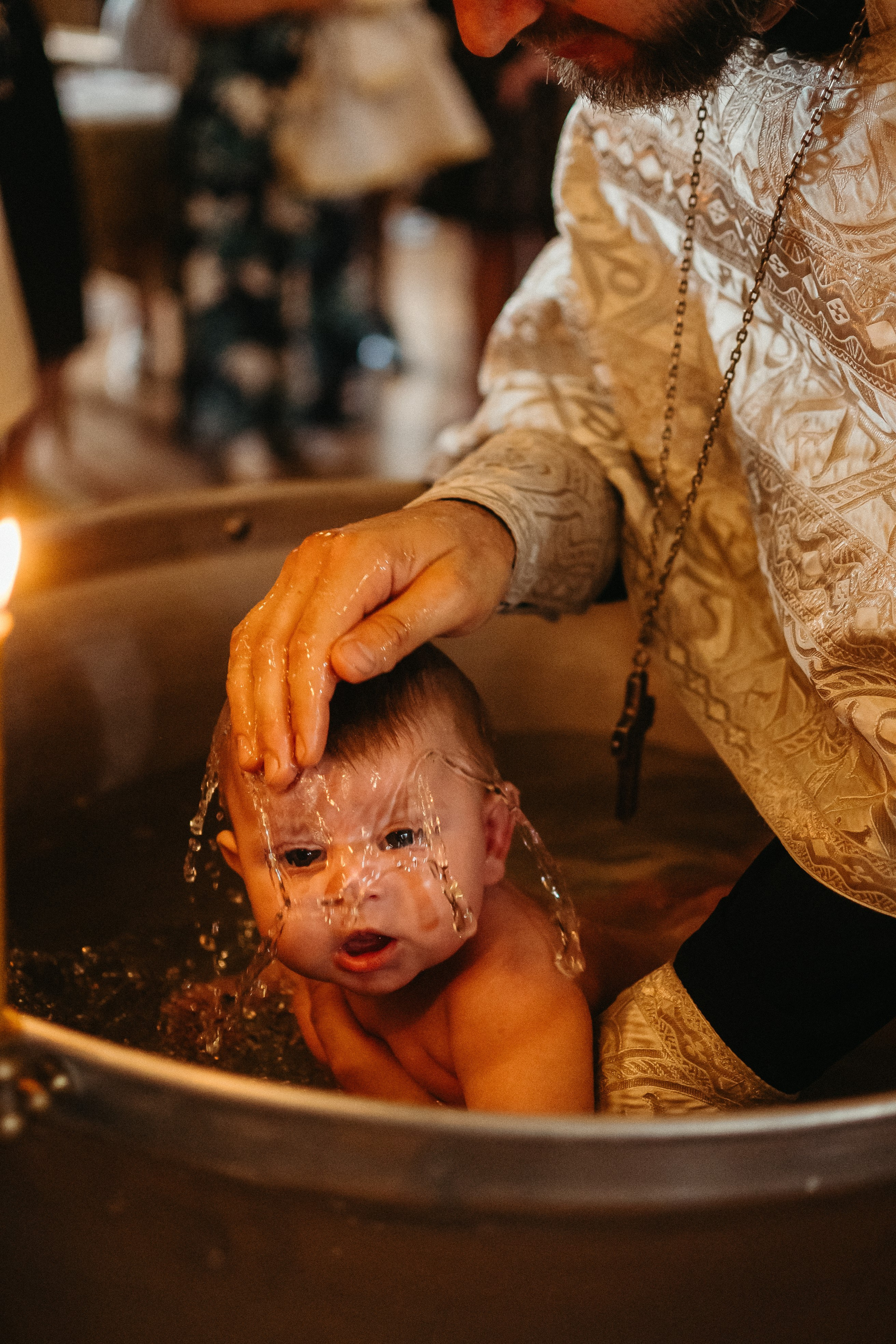 Крупный план священника и младенца во время таинства крещения, репортажная съемка