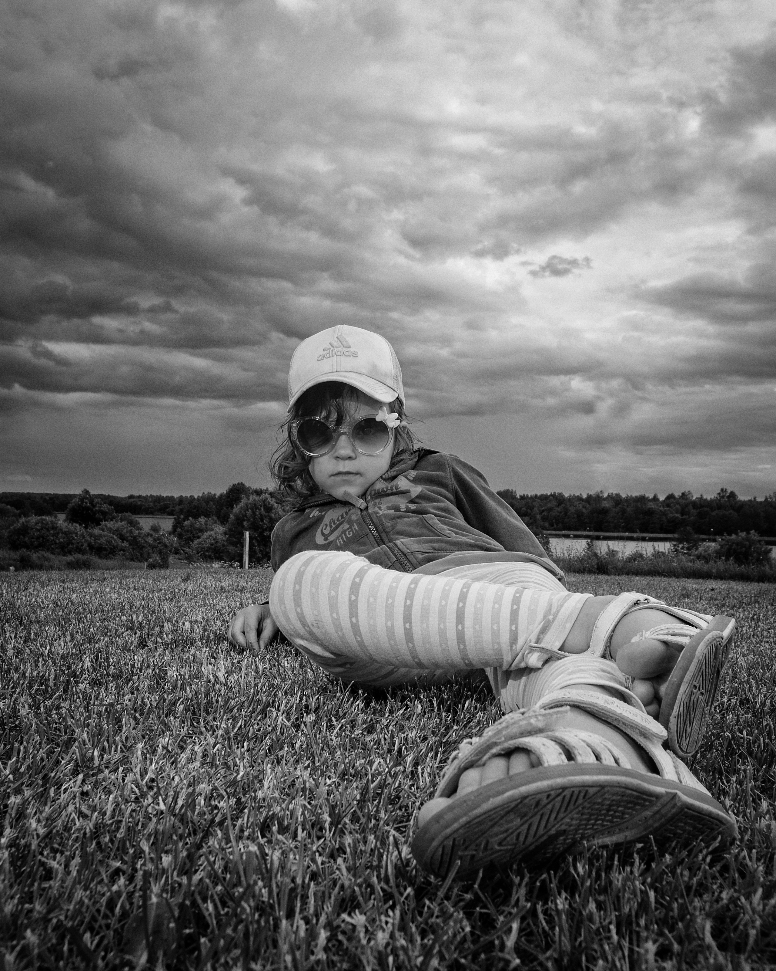 девочка сидит на траве в кепке