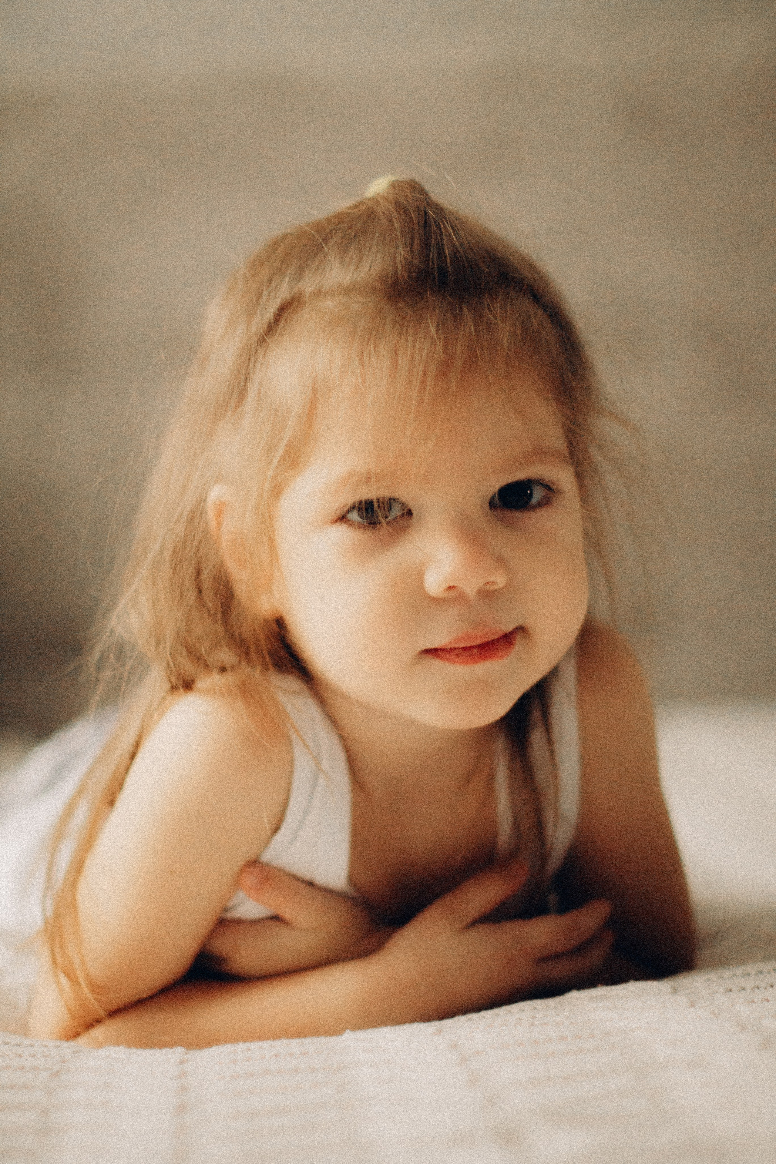 Портрет девочки двух лет, девочка лежит на животе смотрит прямо, домашняя фотосессия 