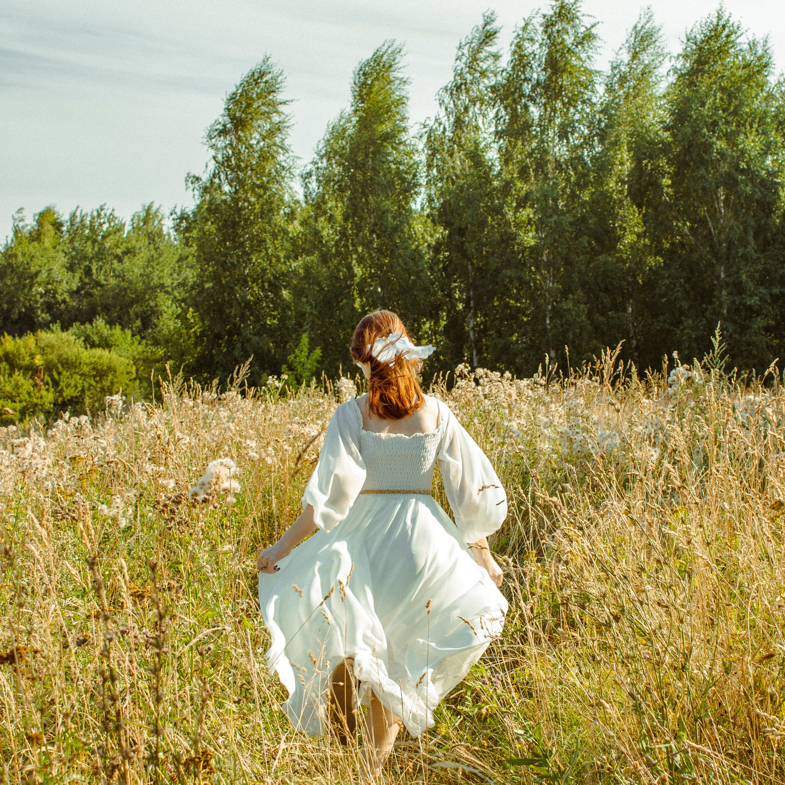 Девушка в белом платье убегает в поле