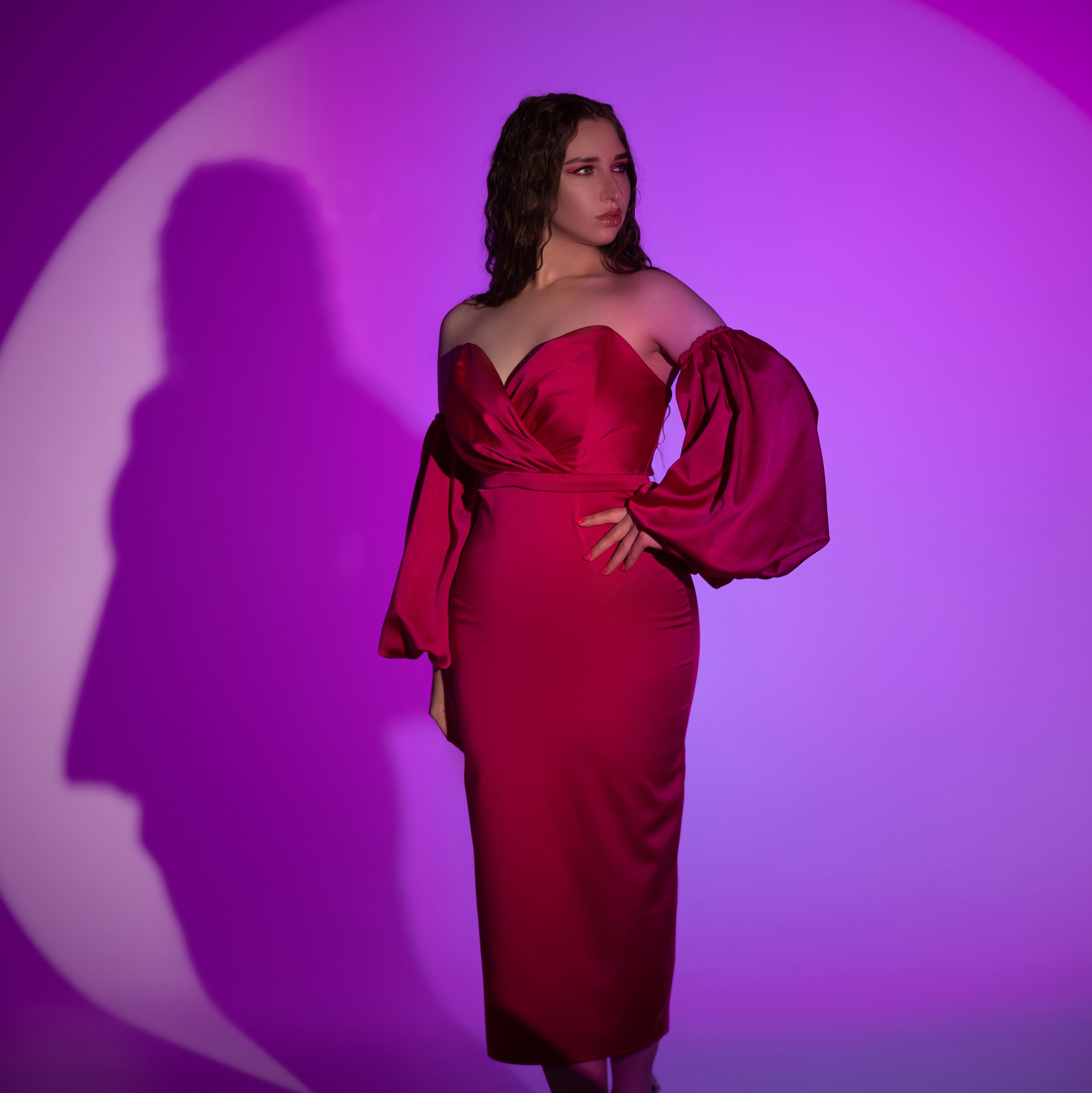 девушка в платье цвета фуксия в фотостудии на циклораме в цветном свете