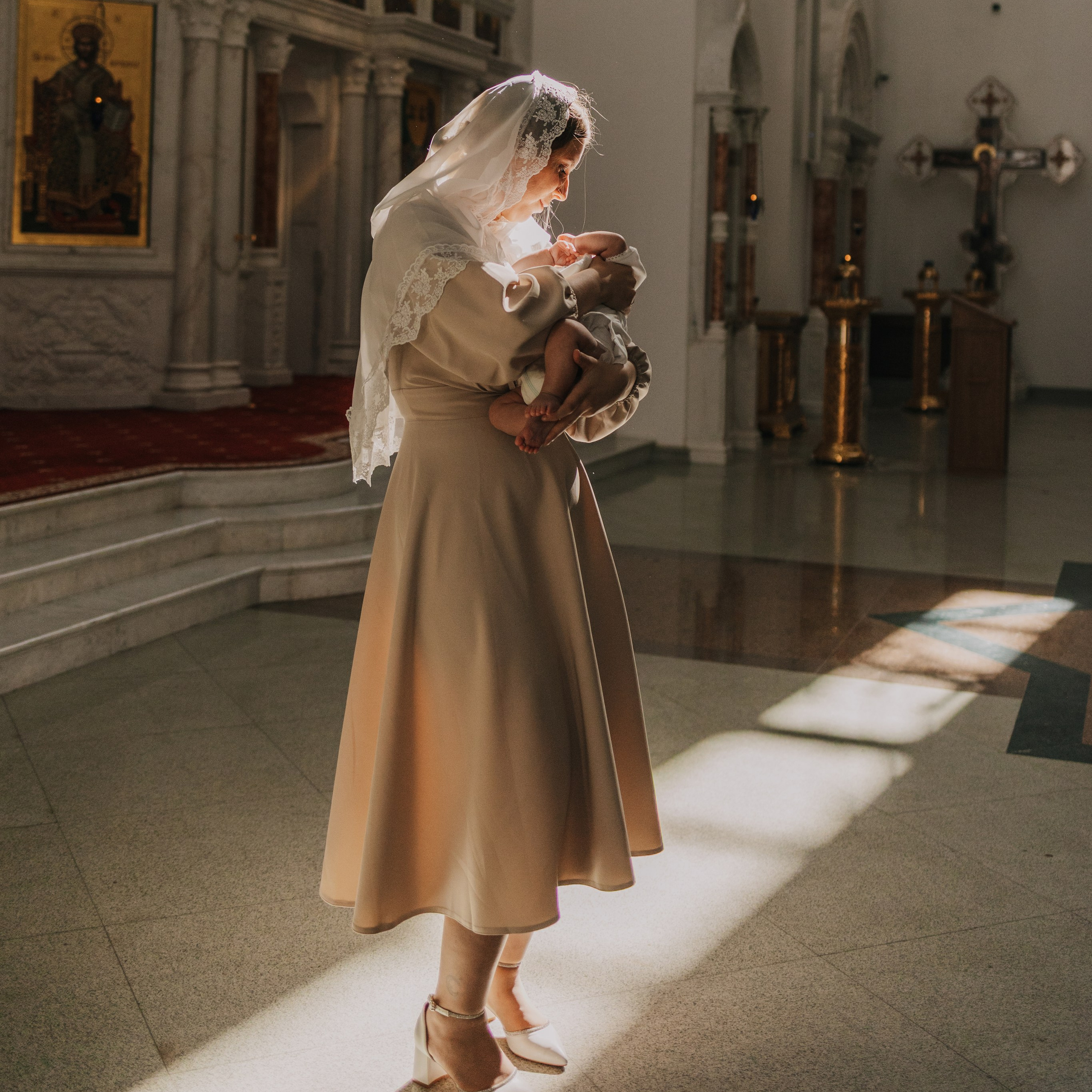 Крещение фотосессия: Ребенок в светлом наряде, улыбающаяся мама.