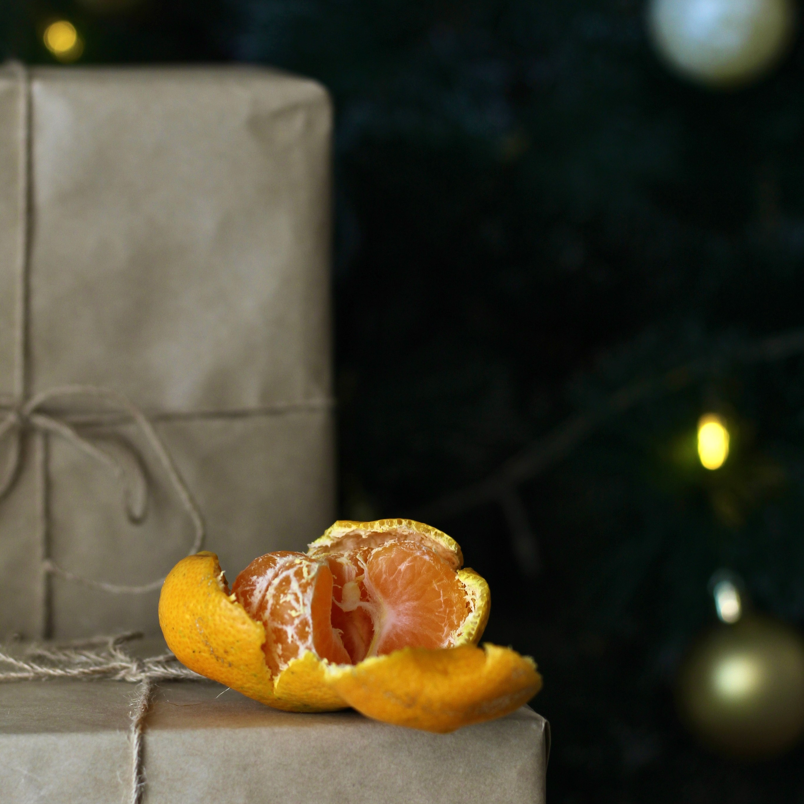 Мандарин на фоне новогодней елки и подарочных коробок