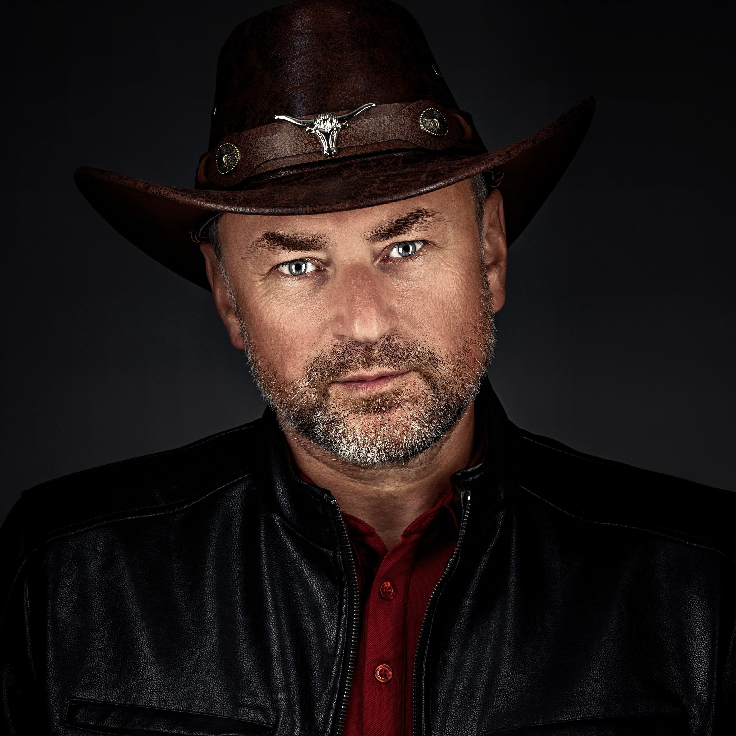 Портрет брутального мужчины в ковбойской шляпе и кожаной куртке.