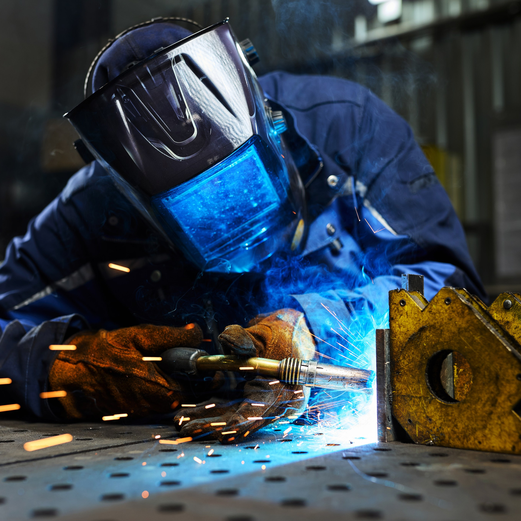 Сварщик в защитной маске работает на заводе