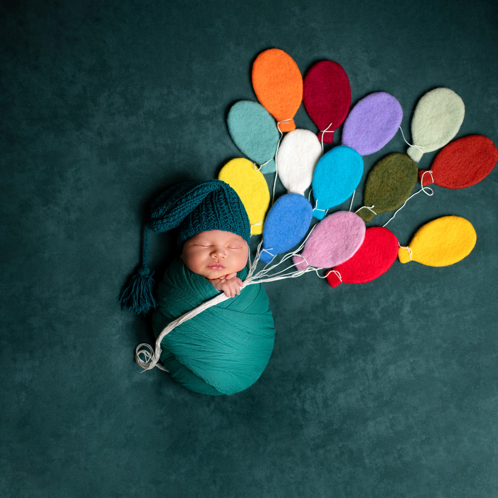 Новорожденный мальчик в колпачке с воздушными шарами