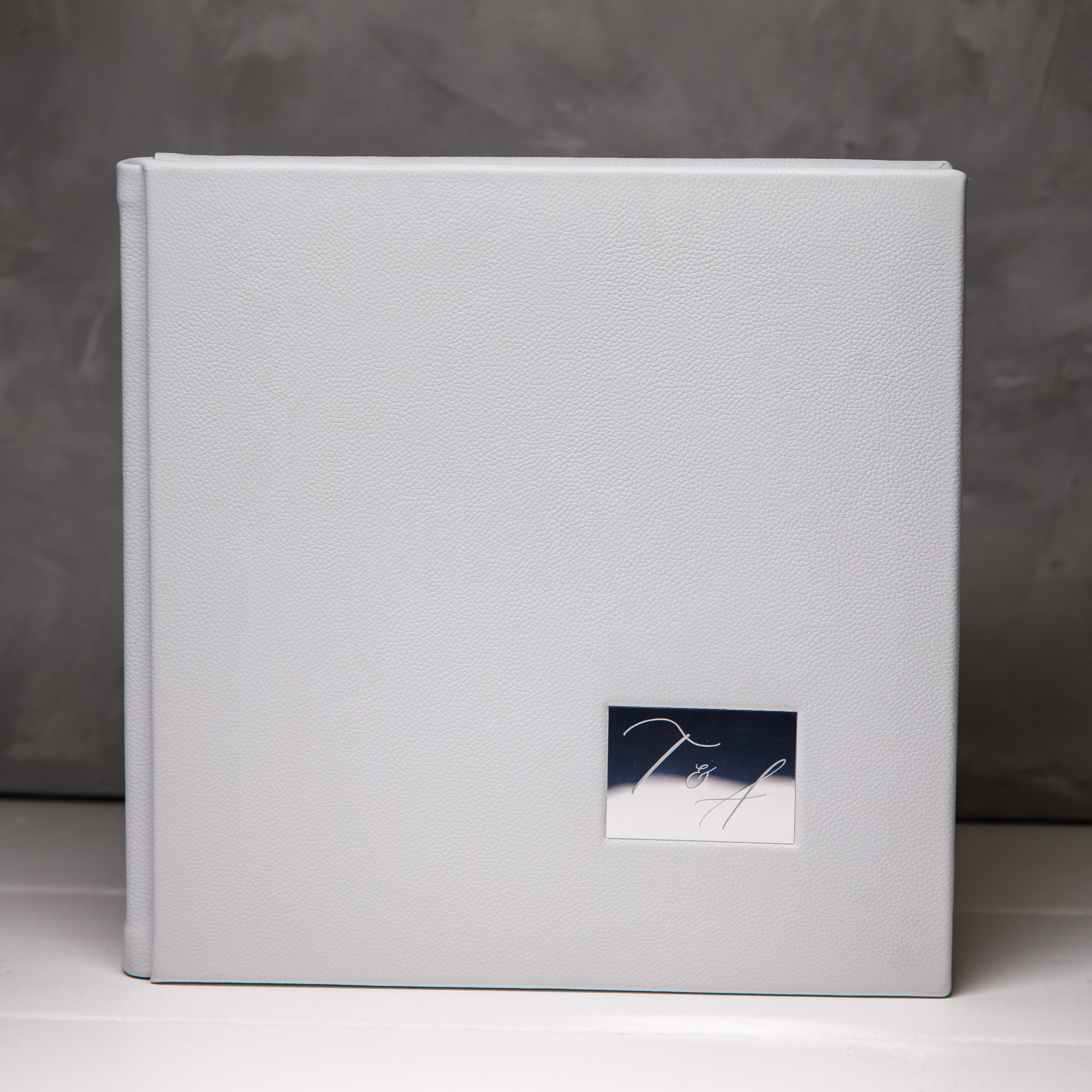 белая кожаная книга с шильдом стоит на столе