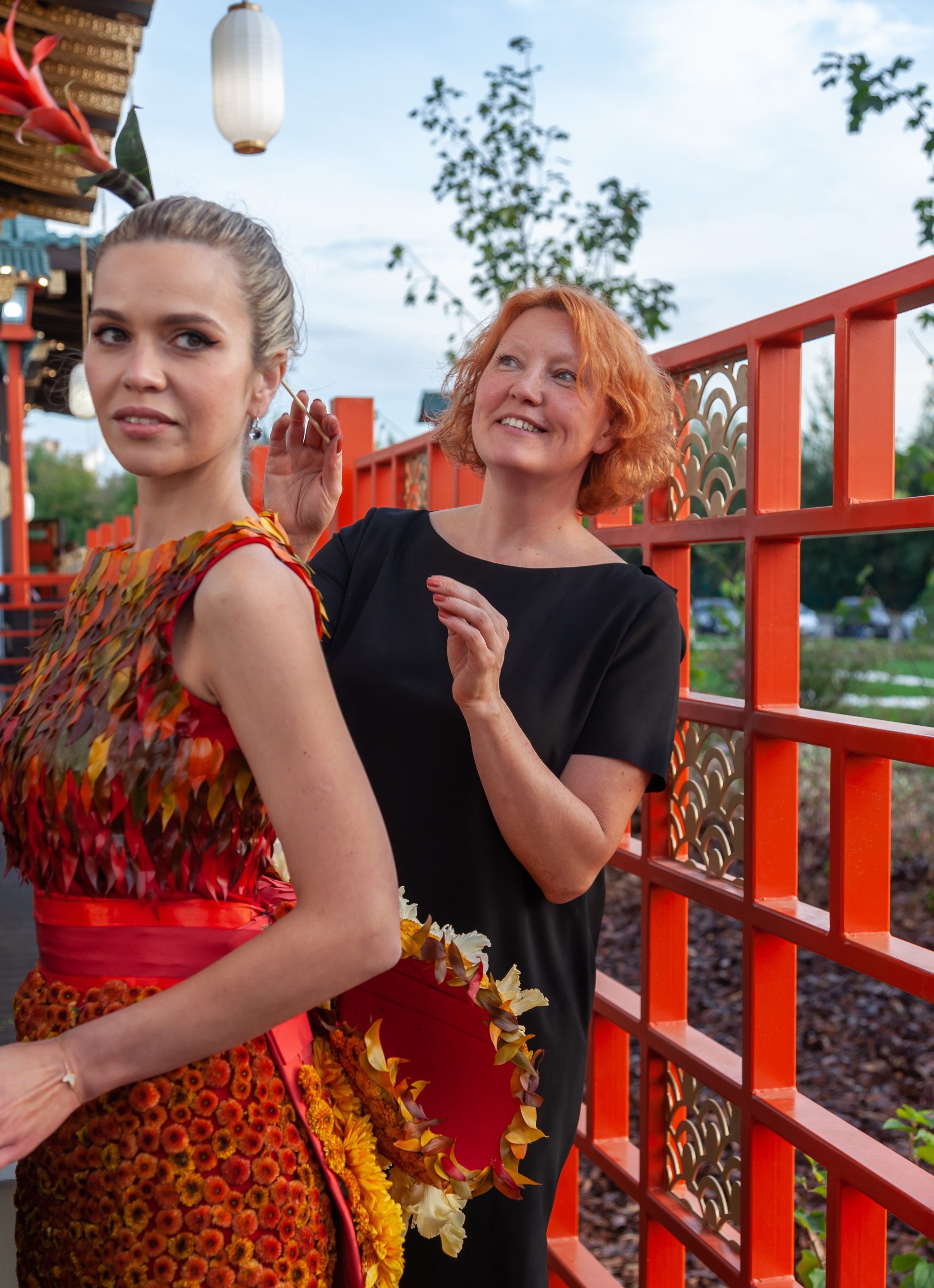 Natalia Zizko adjusting a floral couture piece on model backstage during Artem Krivda fashion presentation, Moscow
