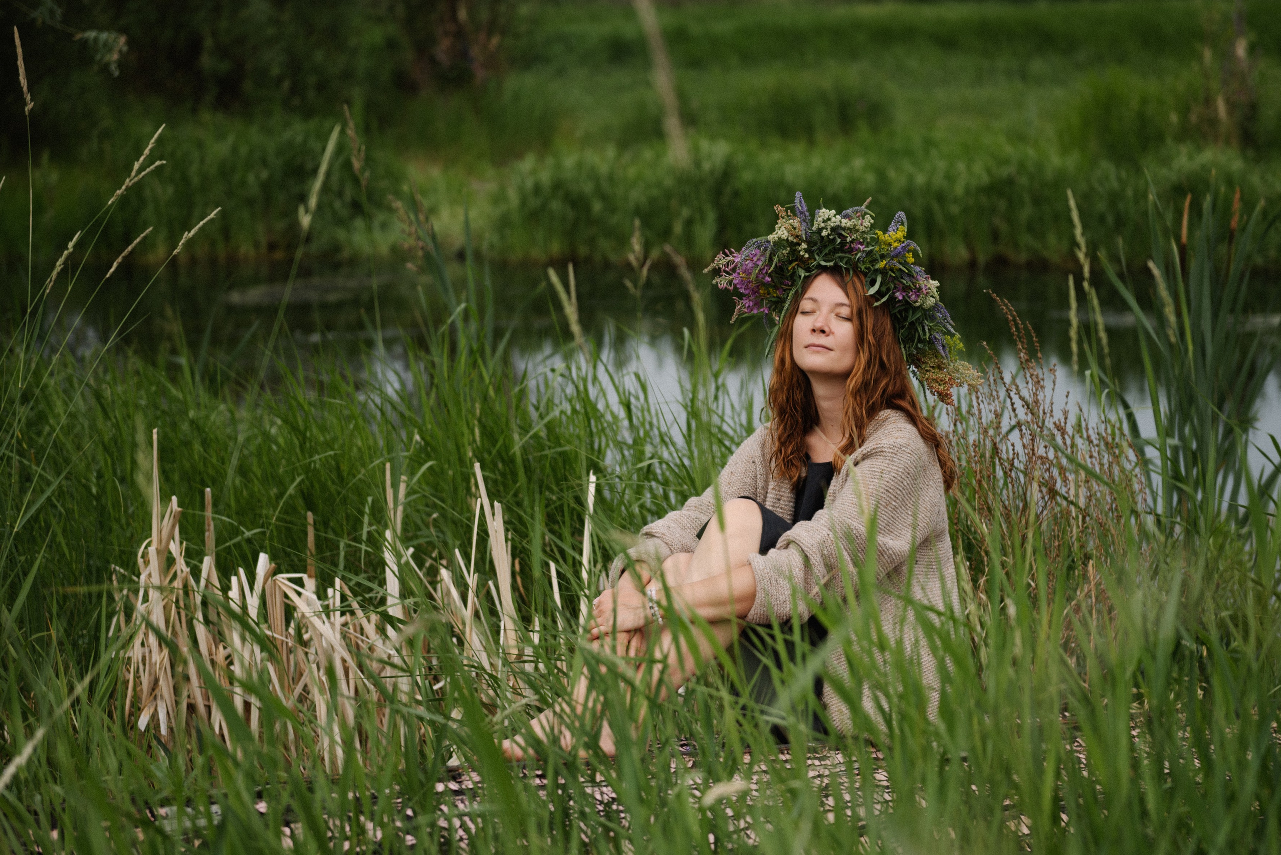 Фото девшушки с венком на голове, в высокой траве на озере