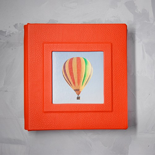 Фотокнига из ярко-оранжевой итальянской кожи с квадратным окном-вставкой на обложке.