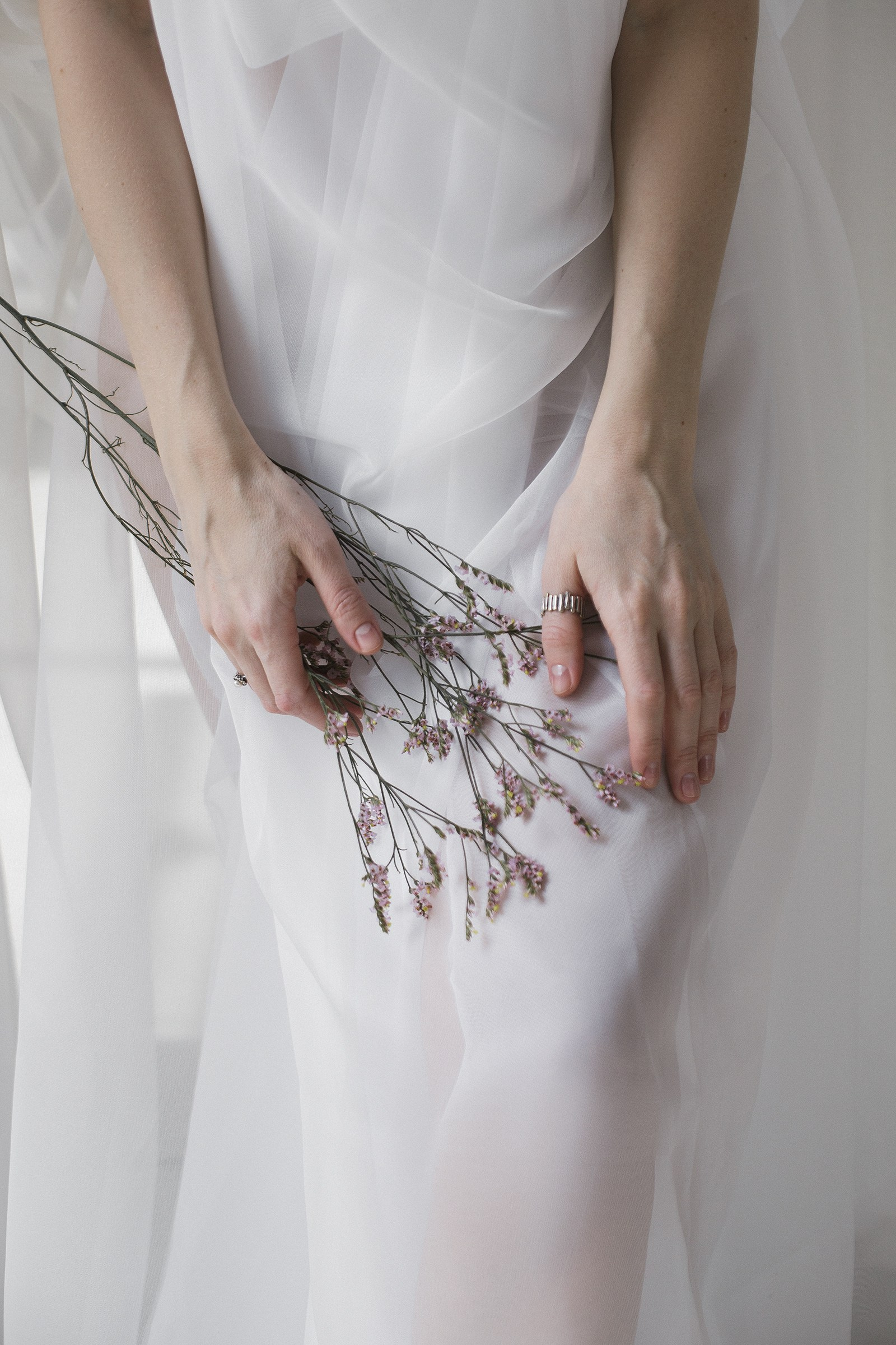 Студийная фотосессия для девушки с использованием белой ткани и весенних цветов.