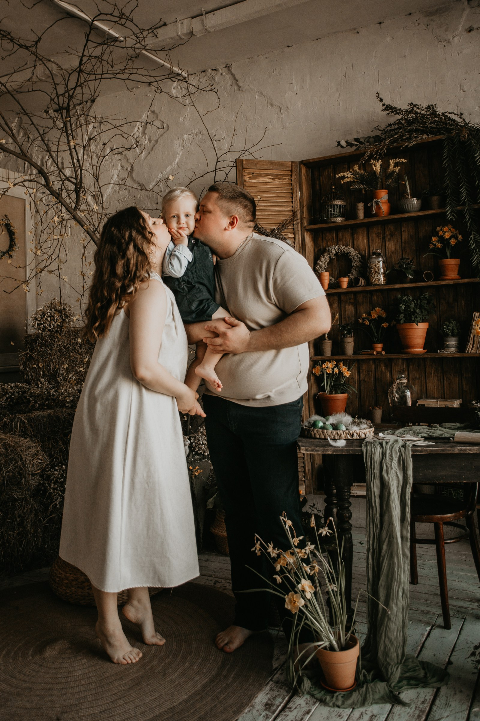 Семейная фотосессия в уютной фотостудии: родители держат ребенка