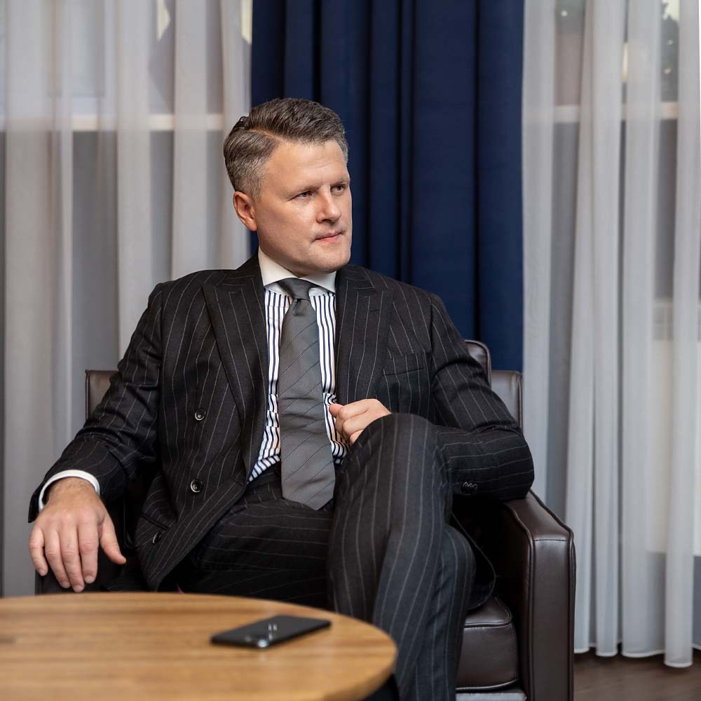 Мужчина в костюме сидит в кресле перед столом