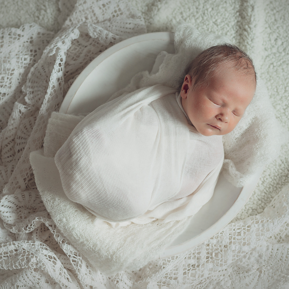 Новорожденный младенец. Запеленала в светлые ткани и кружево. Спящий малыш в корзинке. 