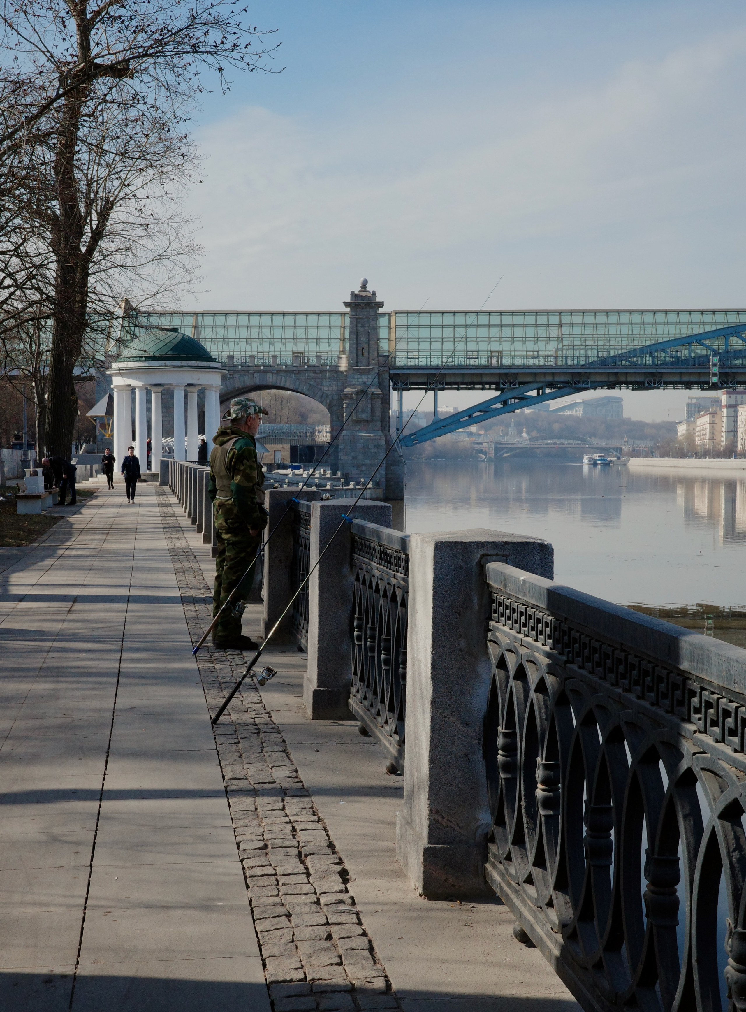 Рыбак в камуфляже с удочкой на набережной у ротонды, Андреевский мост на заднем плане