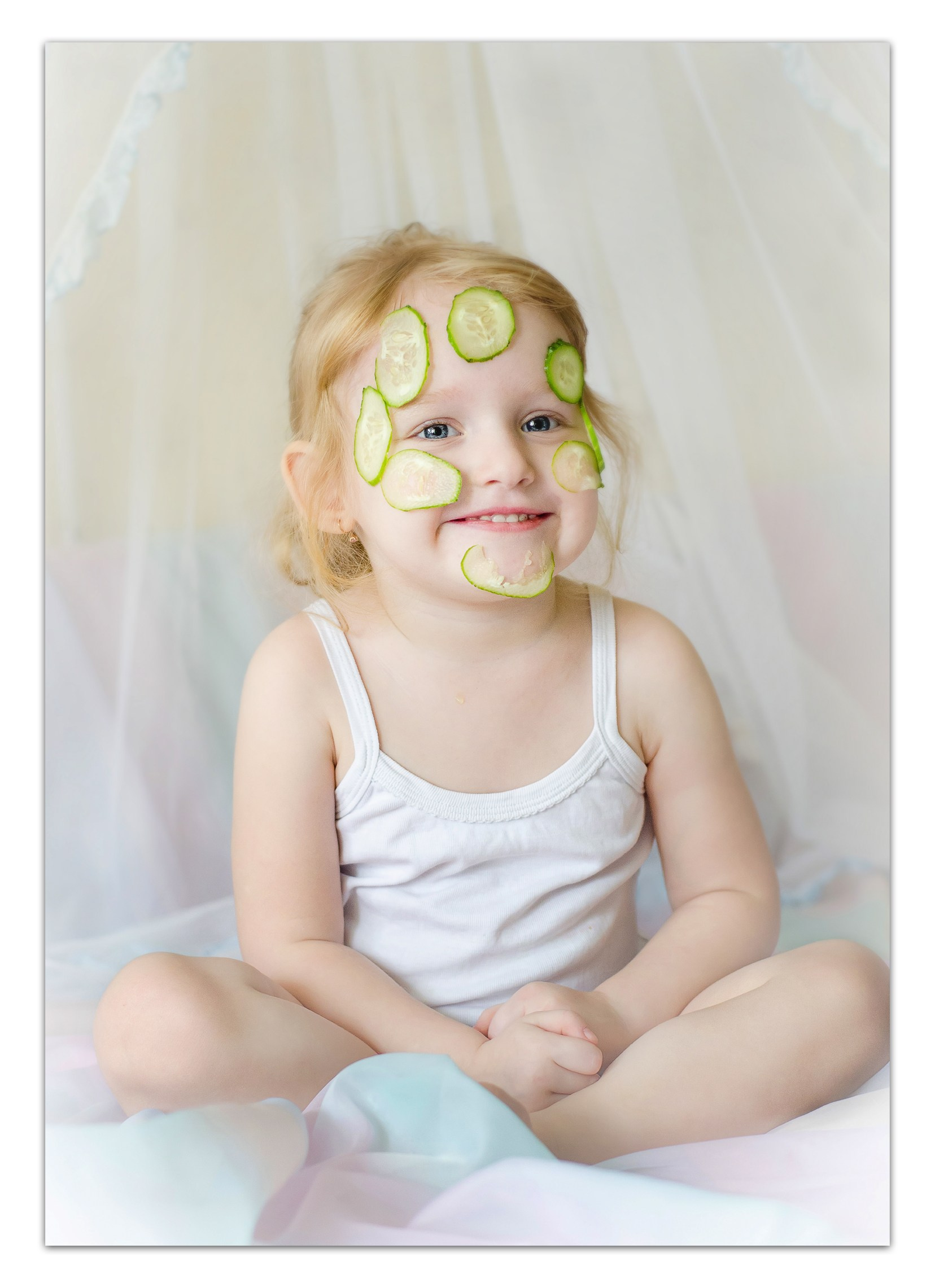 Фотосъемка дома - малыш сидит на кровати в мягком утреннем свете.