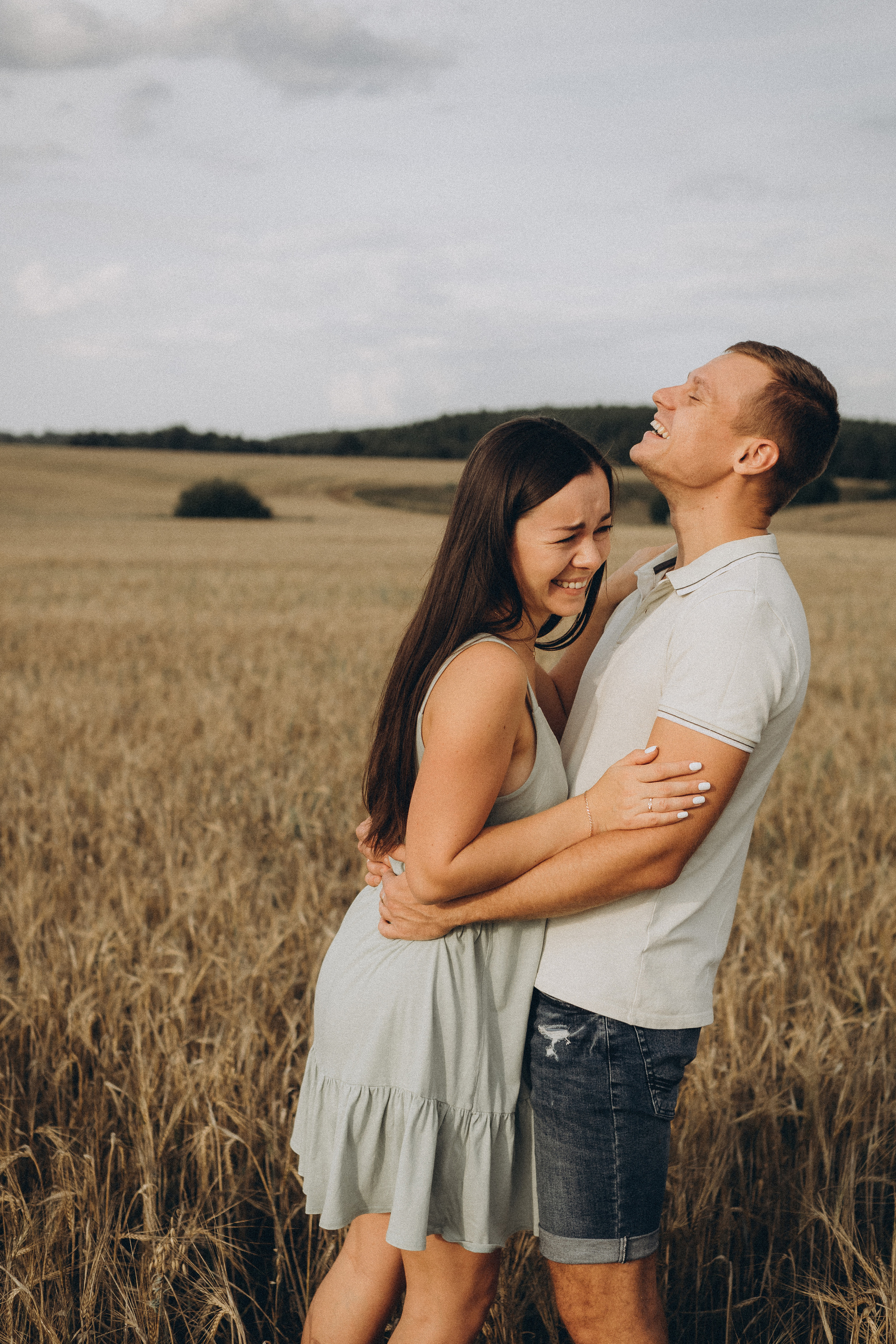 парень с девушкой стоят в поле и смеются