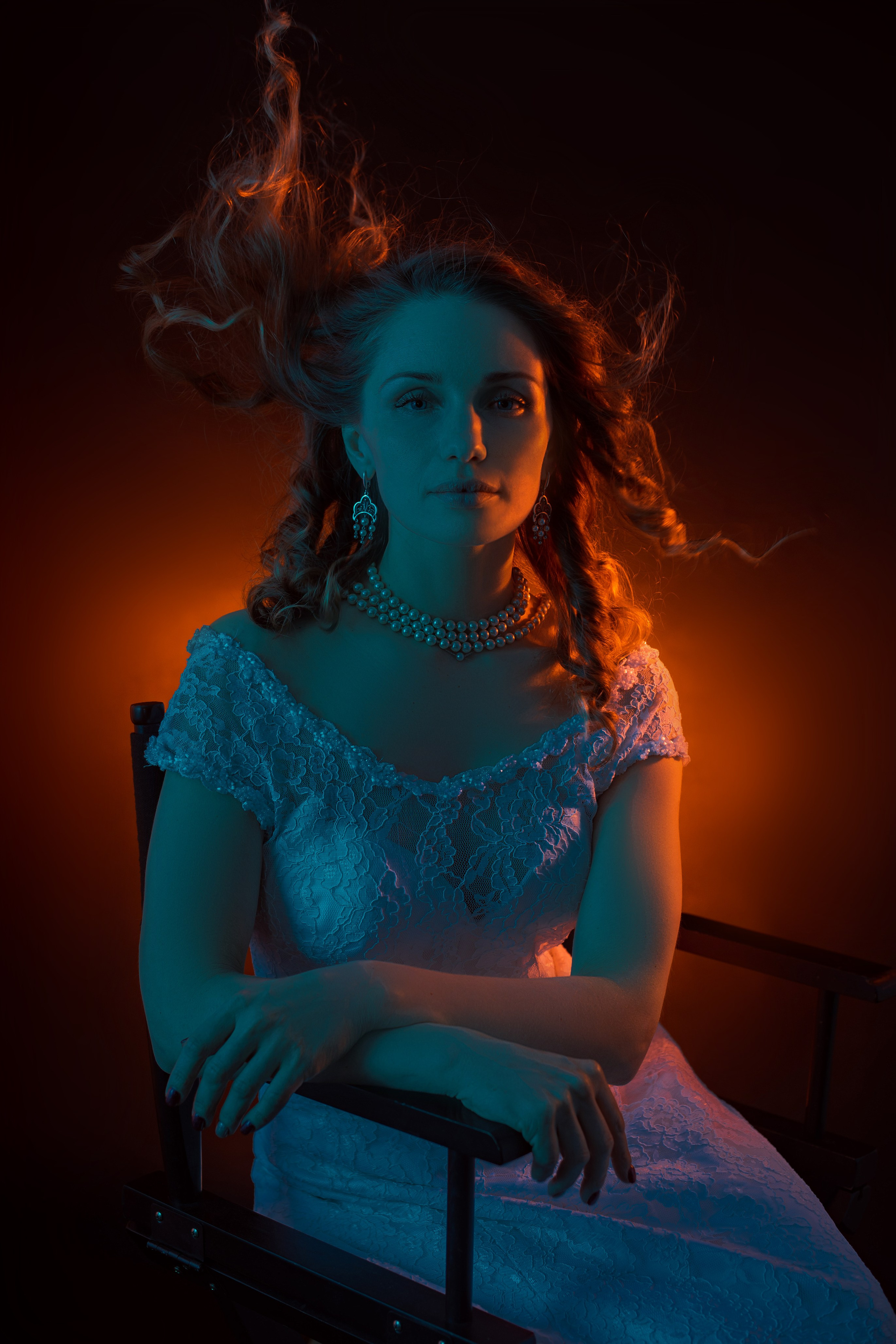 Портрет девушки в белом платье с развивающимися волосами в студии, цветной студийный свет, красно-синий гелевый свет.