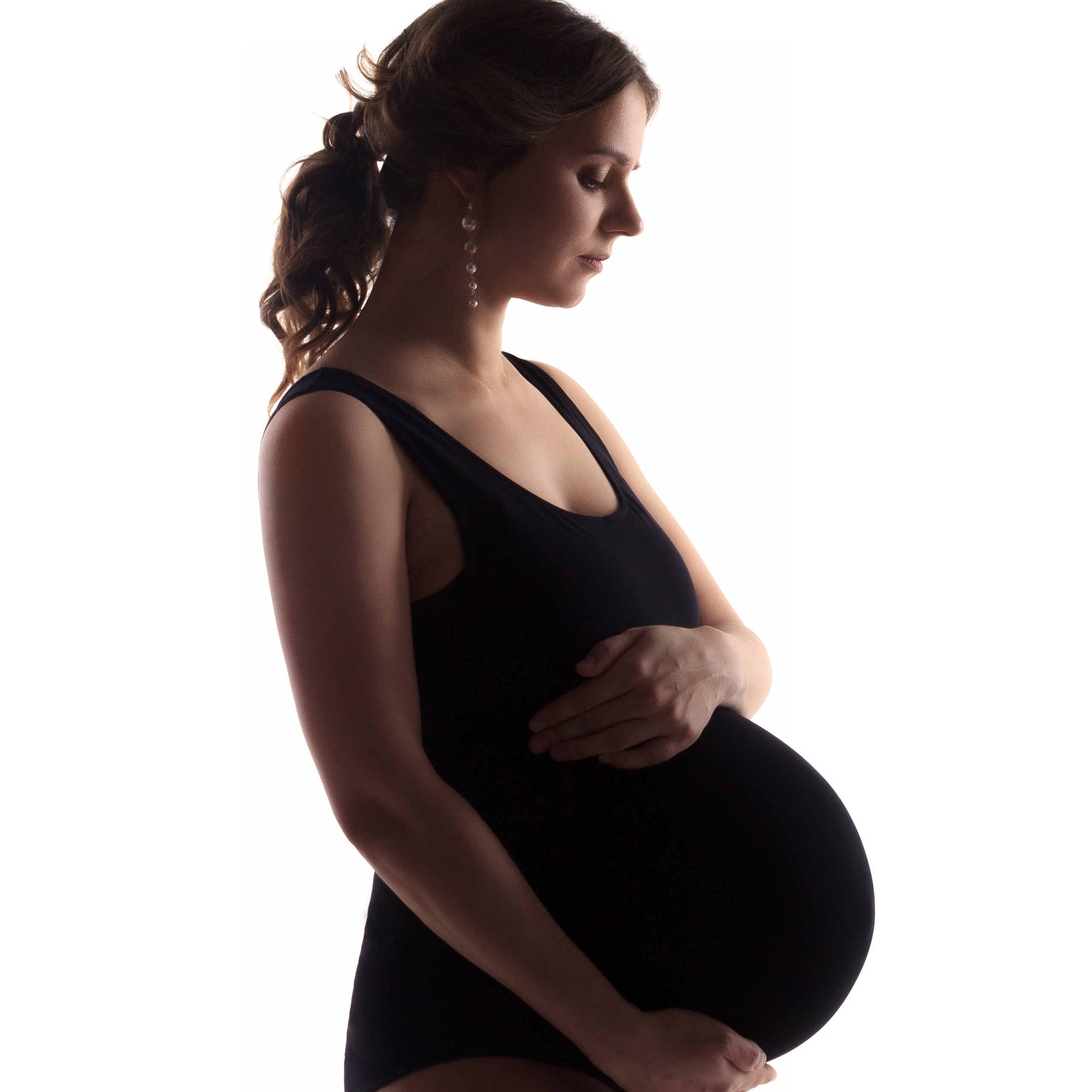 беременная девушка в черном боди нежно обнимает животик