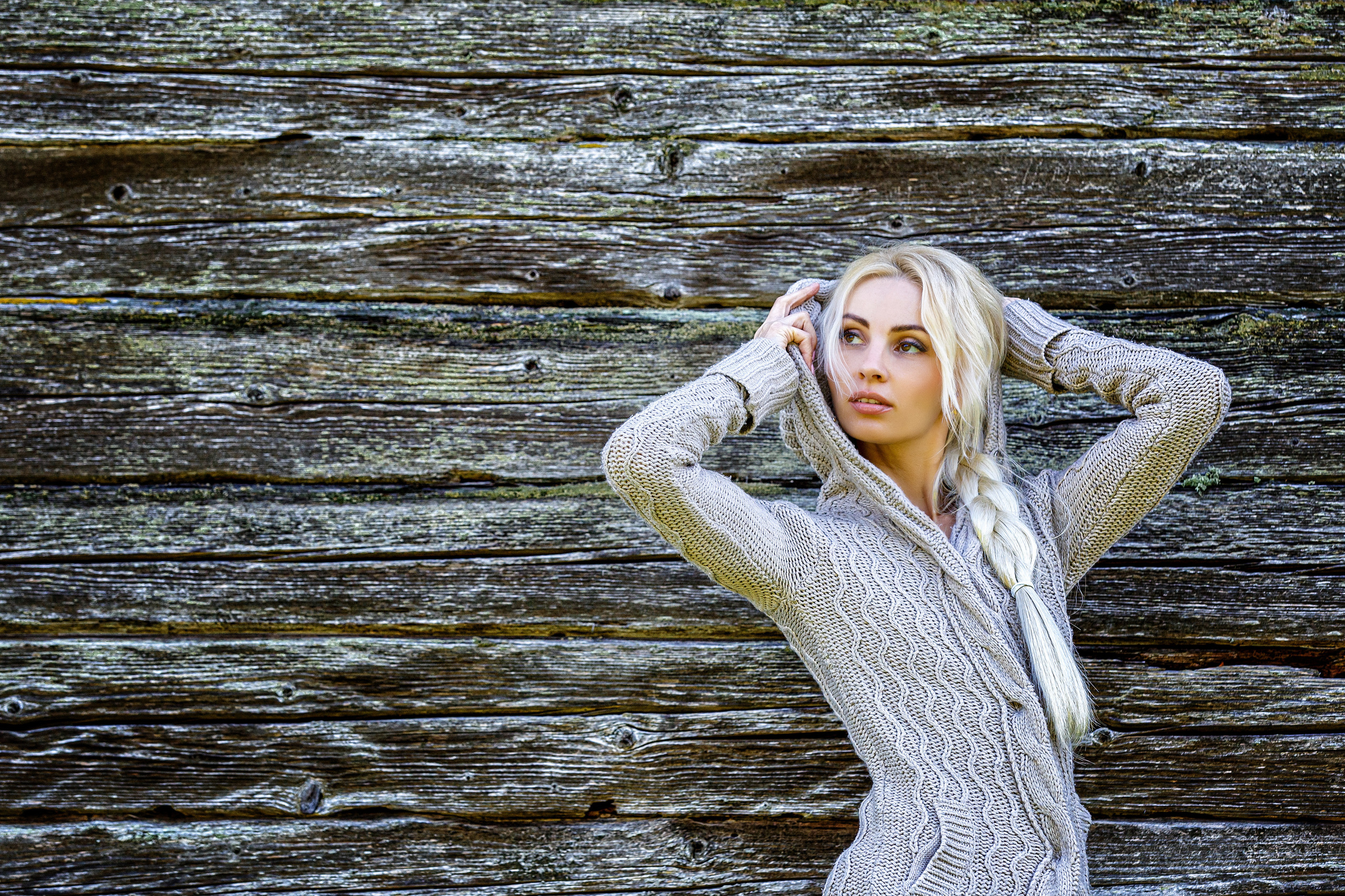 блондинка в сером кардигане на фоне серых бревен