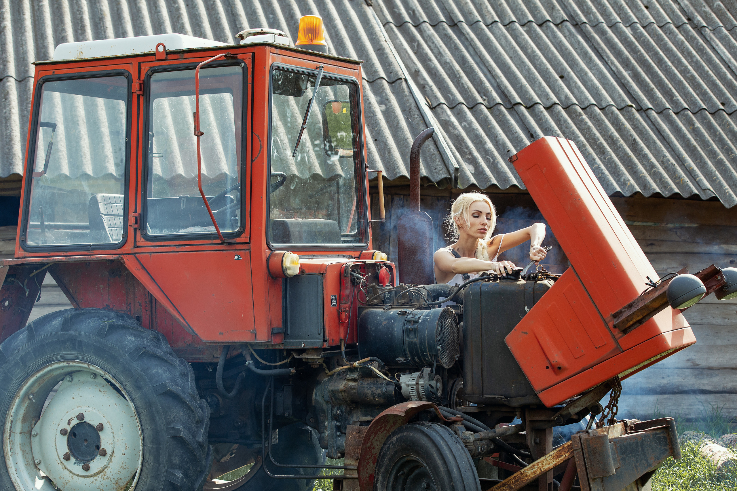 девушка с гаечным ключом ремонтирует трактор