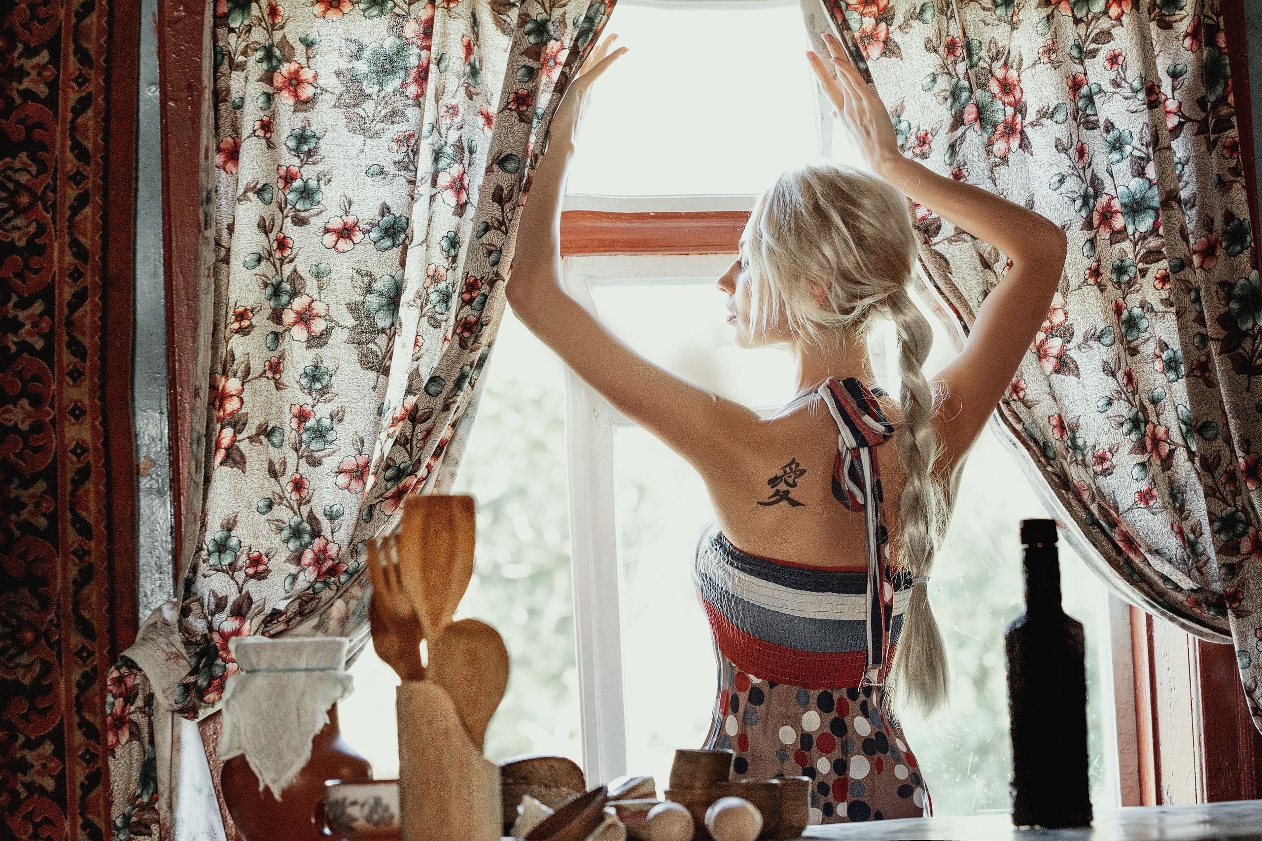 девушка со спины занавешивает окно