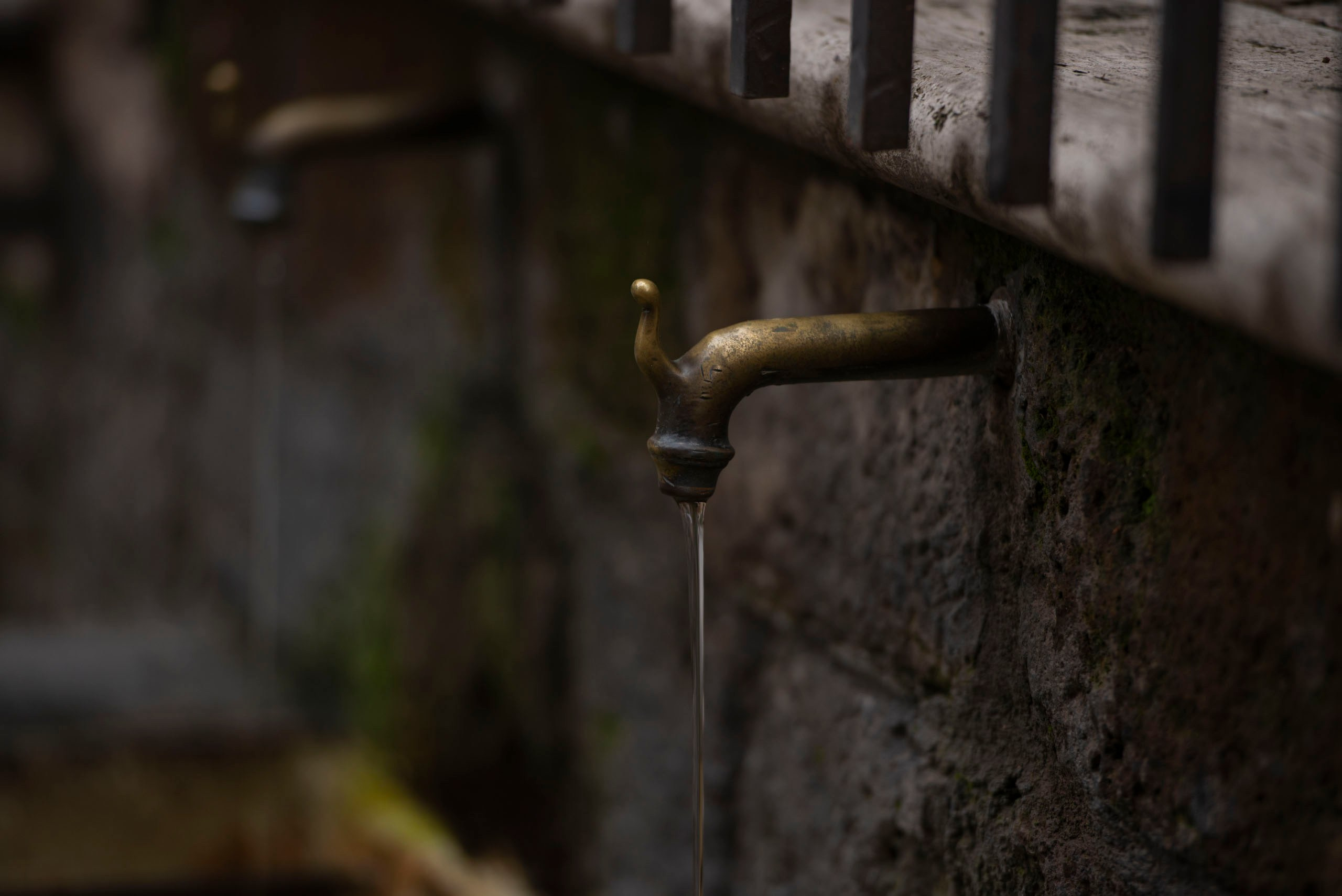 Фотография старинного медного крана на стене в городе Пьенца, Италия