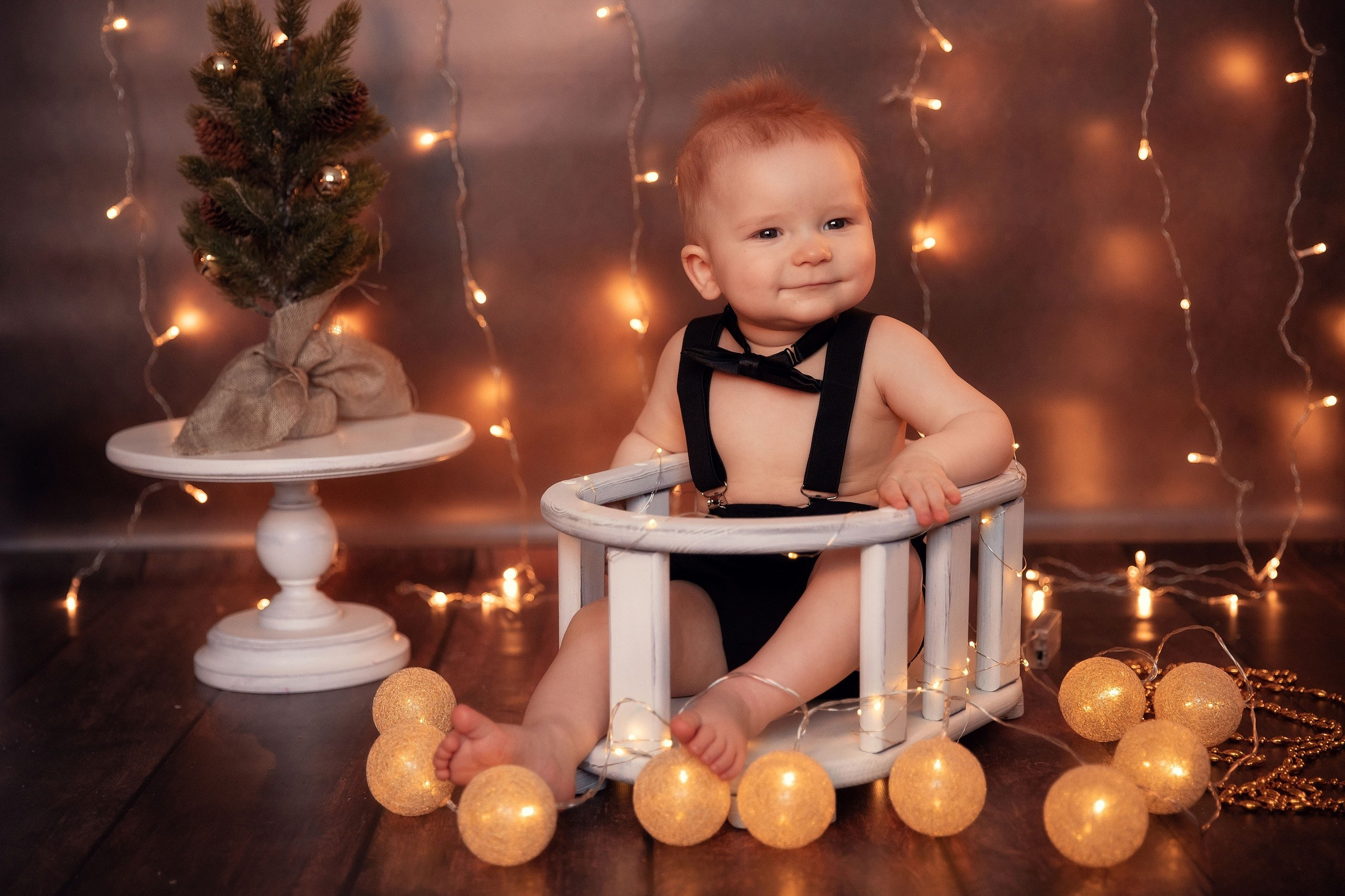 Милый малыш сидит среди новогодних шариков