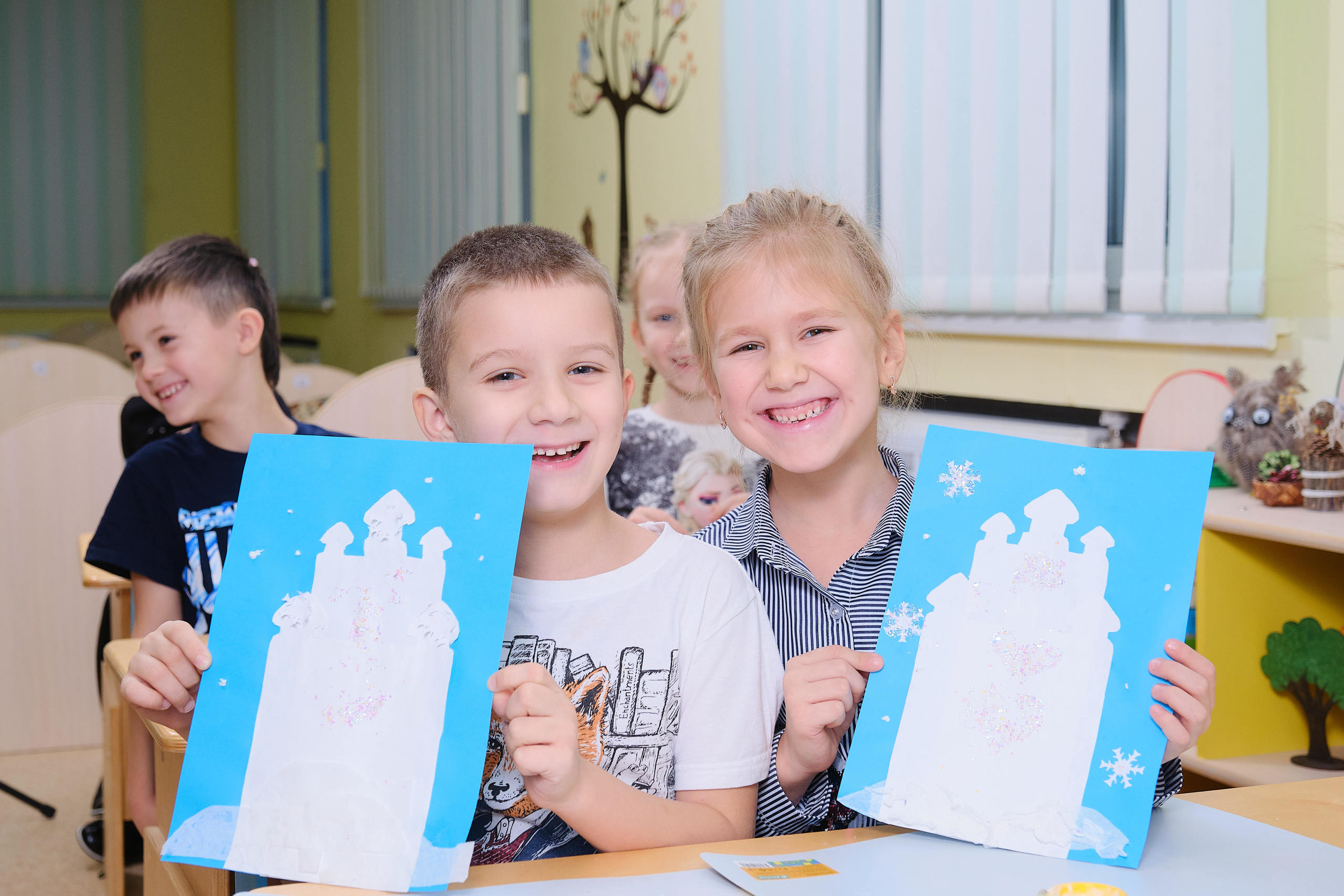 мальчик с девочкой в детском саду показывают свои поделки