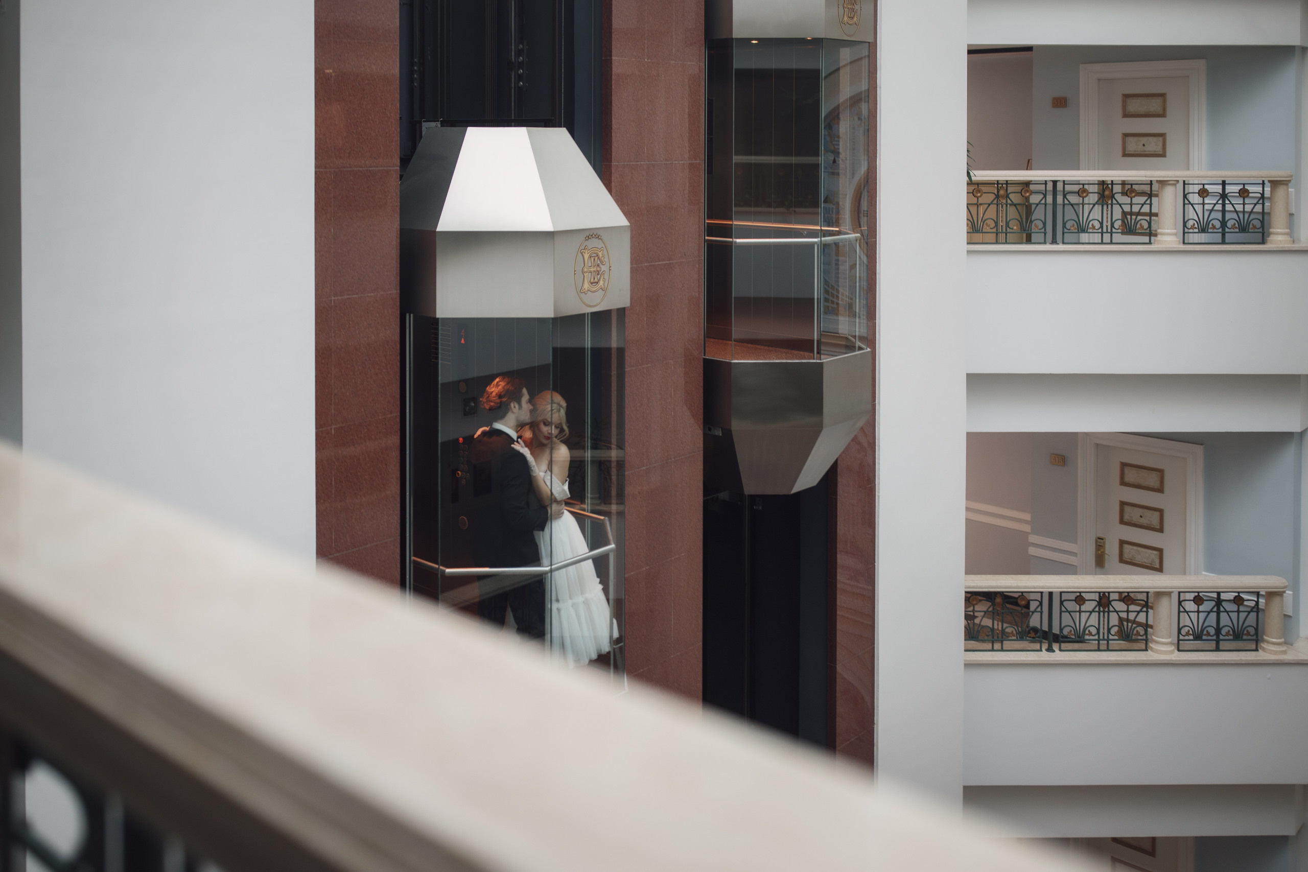 Невеста и жених спускаются на лифте в отеле к месту бракосочетания. 