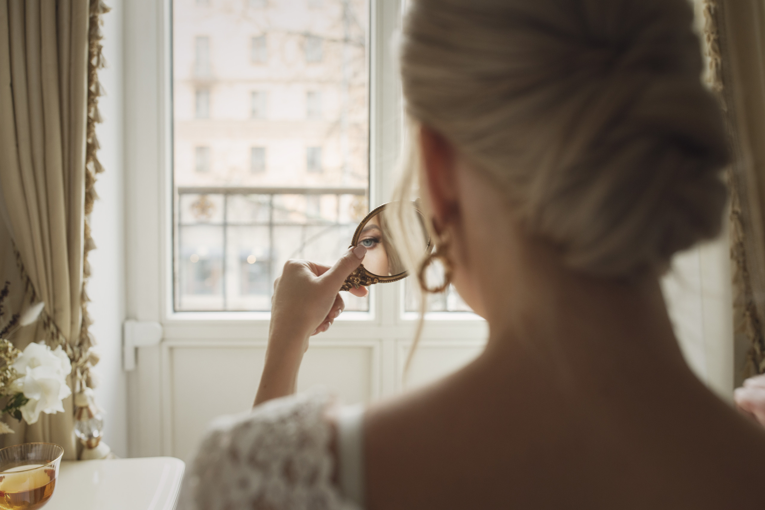 Красивая, сексуальная невеста смотрит в зеркало, сидя на кровати в гостинице. 