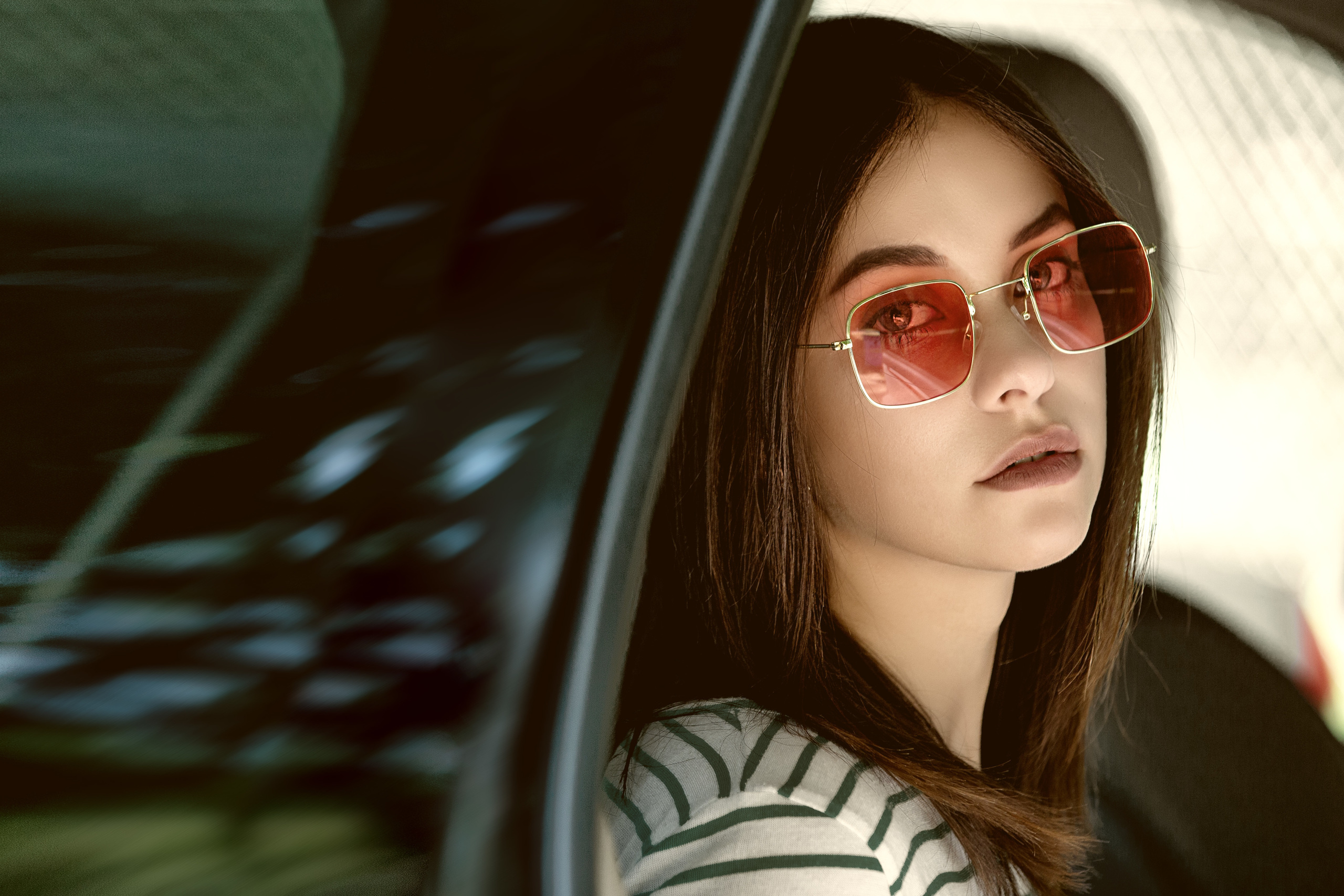 девушка в темных очках в машине смотрит на вас.