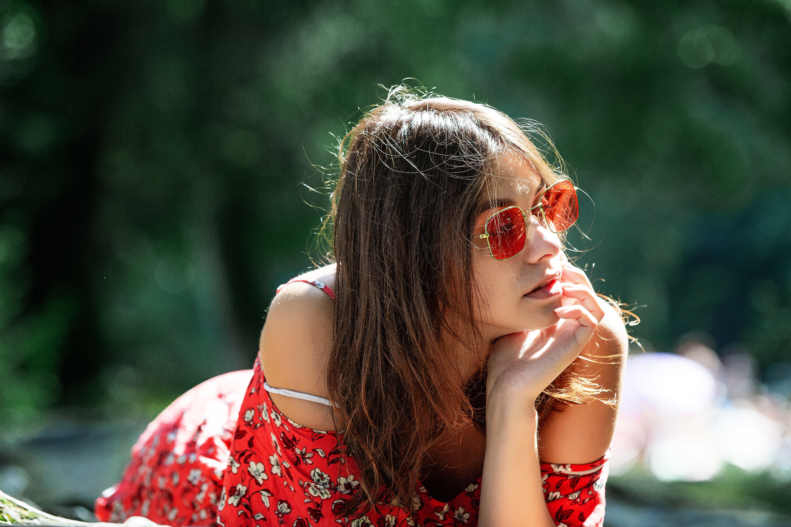 девушка в красном платье лежит на животе.