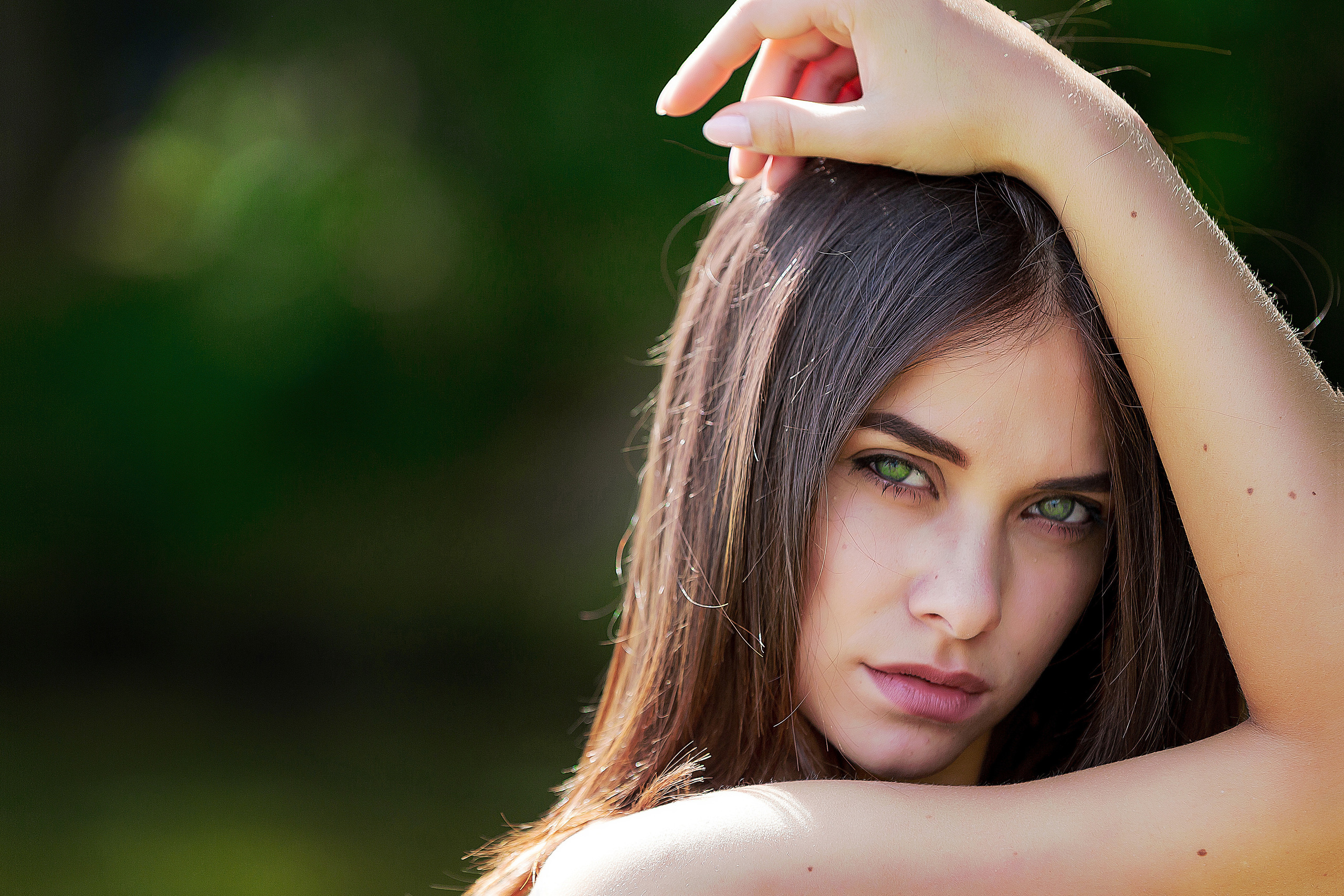 крупный портрет девушкис зелеными глазами на размытом темно-зеленом фоне.