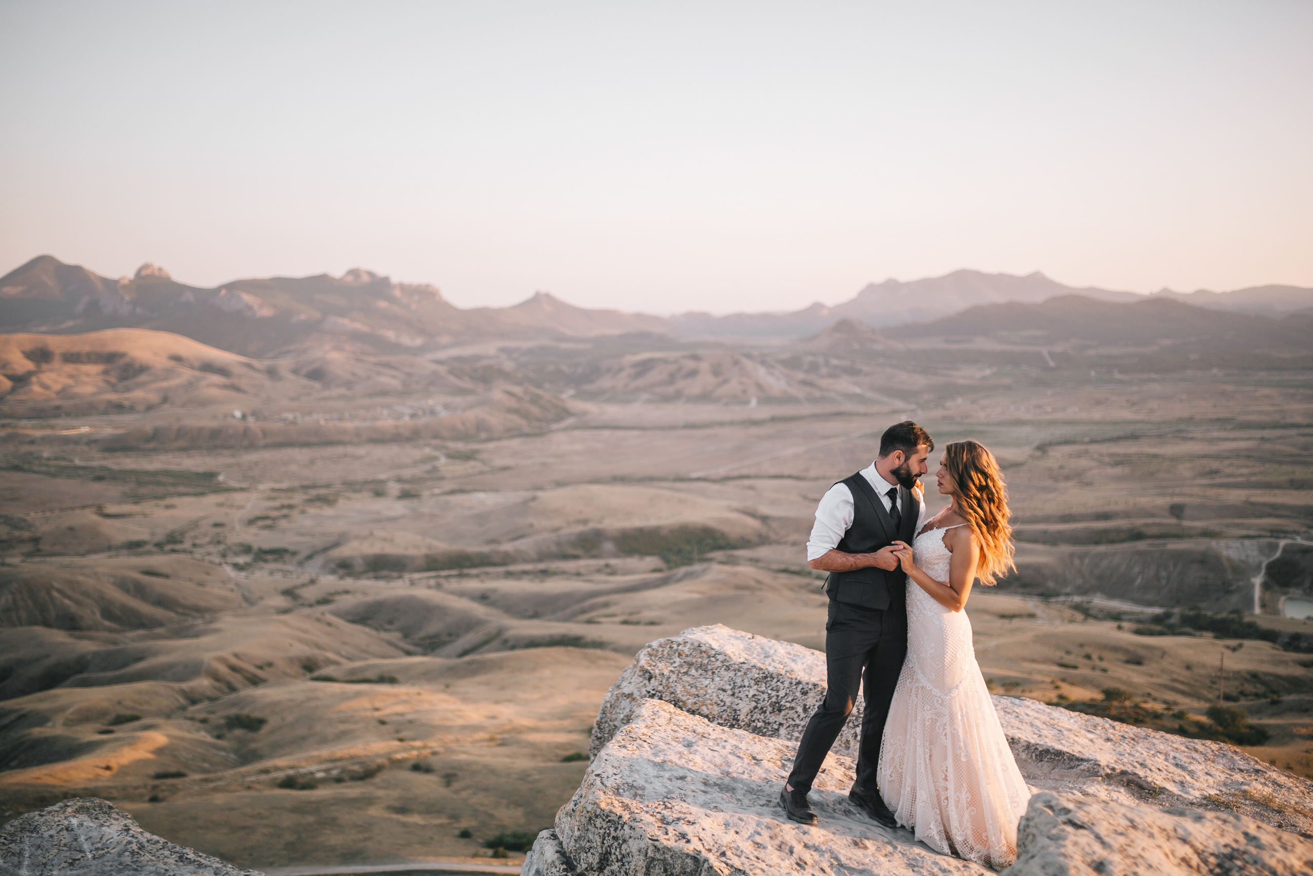 Невеста с женихом стоят на обрыве высокой горы