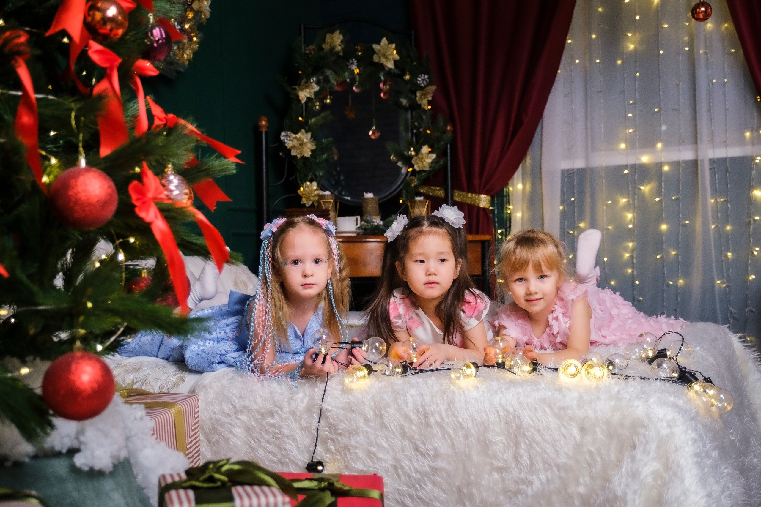 В студийной новогодней локации три ребёнка лежат на кровати