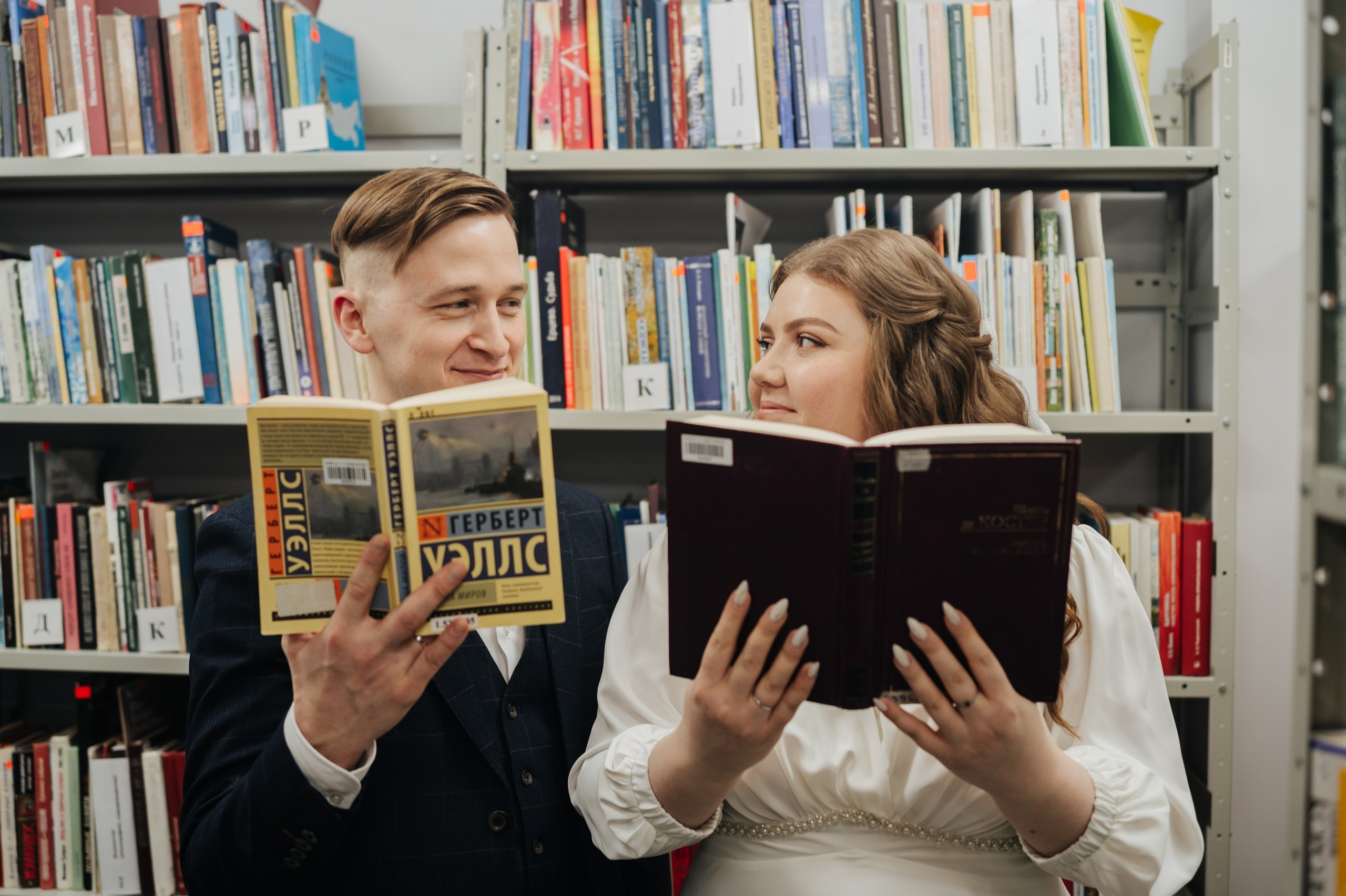 Невеста стоит на фоне свадебной арки, показывает фотографию жениха