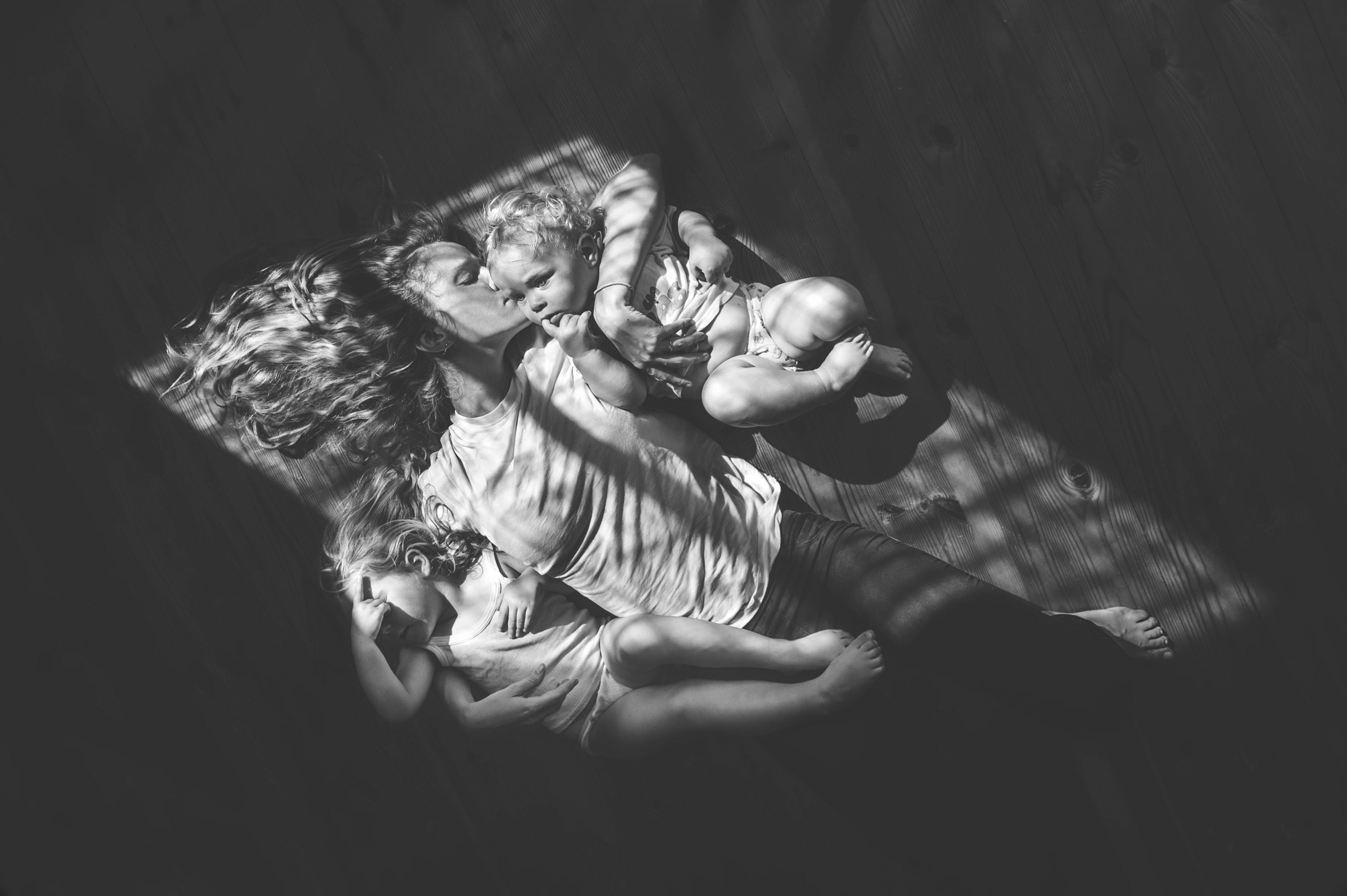 черно-белая фотография про маму с двумя детьми в световом луче от окна стала победителем в конкурсе Росфото "Семейный фотограф" в номинации Семейный портет