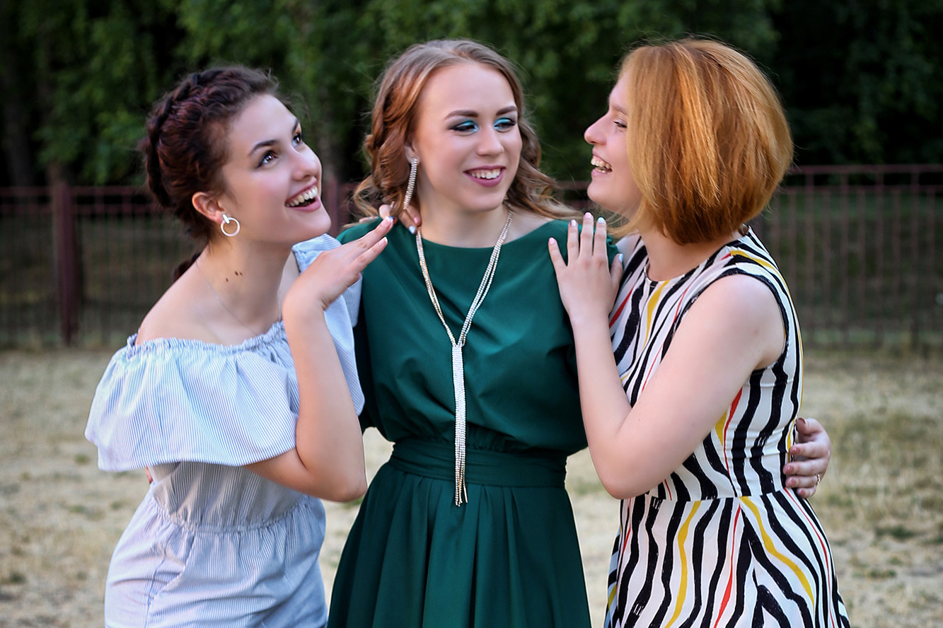 три девушки в вечерних платьях мило разговаривают