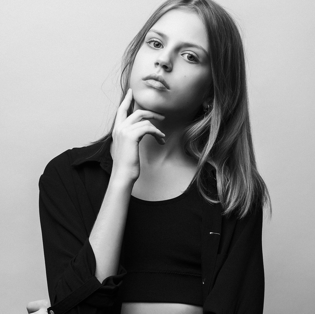 Ученица в белой рубашке с красивыми лококами облокотилась на парту.