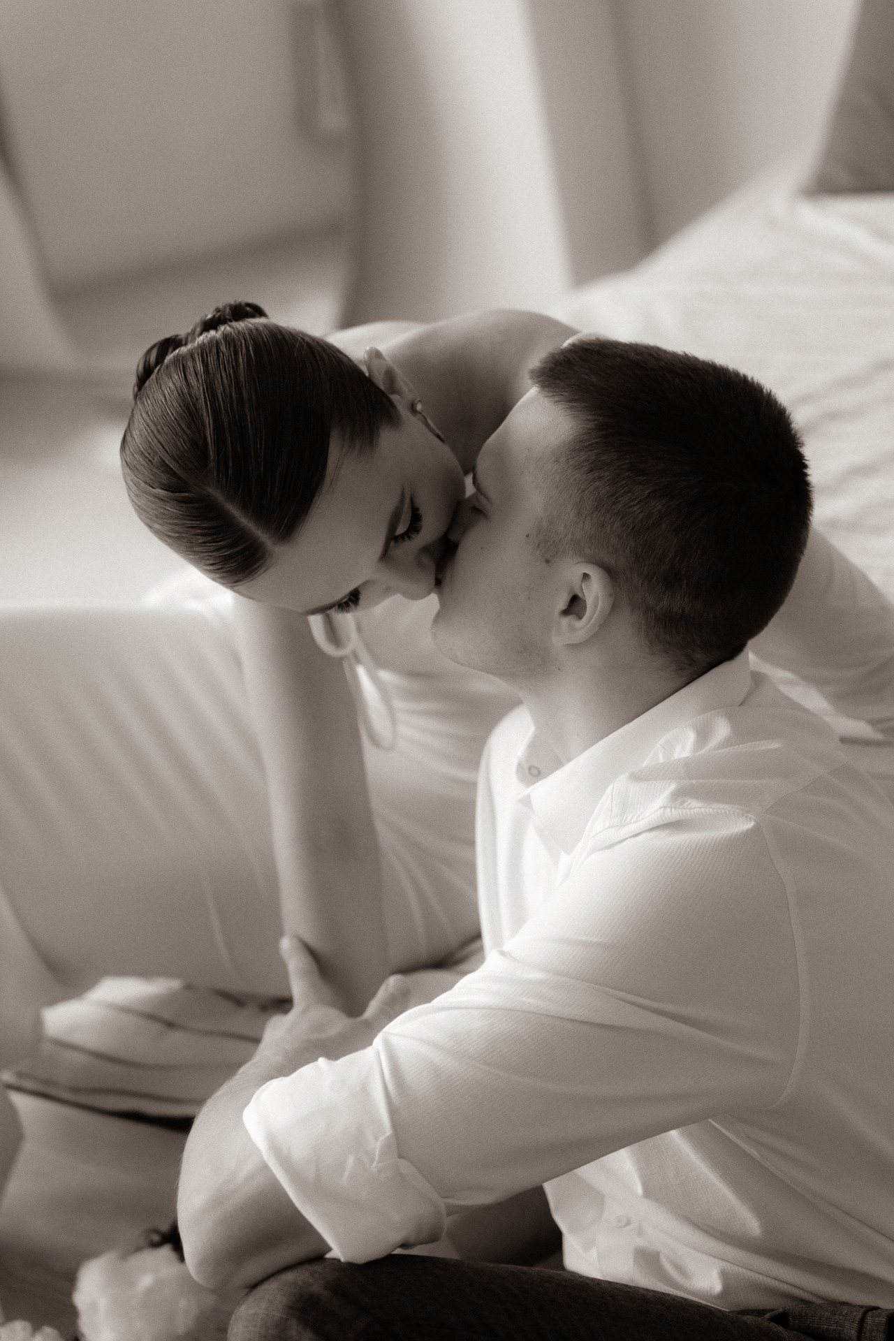 Кадр в черно-белом цвете, на котором невеста нежно целует жениха.