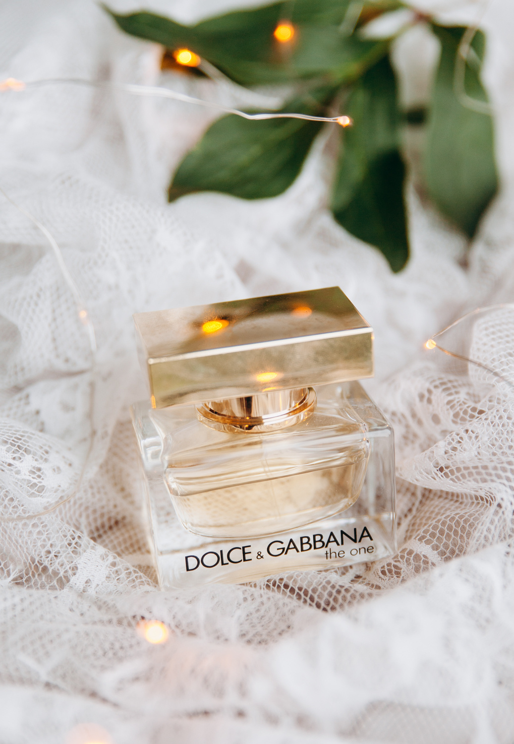 Флакон духов стоит на фоне кружевного халата невесты белого цвета