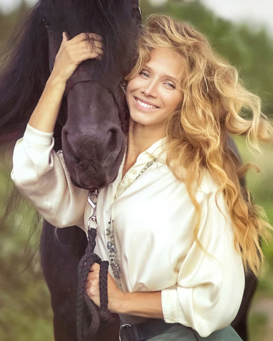Девушка с красивыми длинными волосами обнимает своего коня